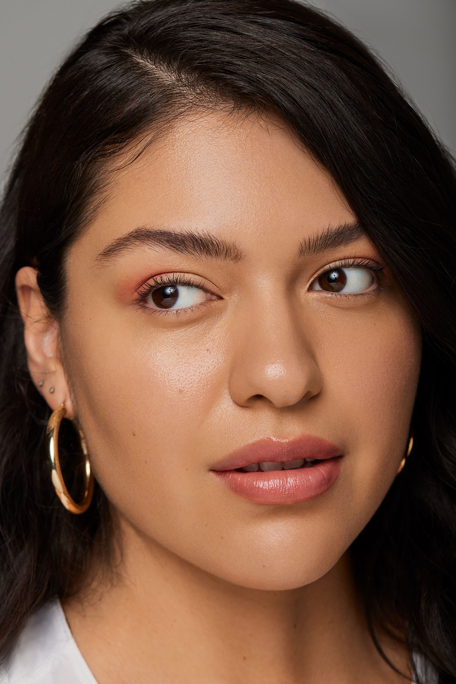 a woman in a white shirt and gold hoop earrings