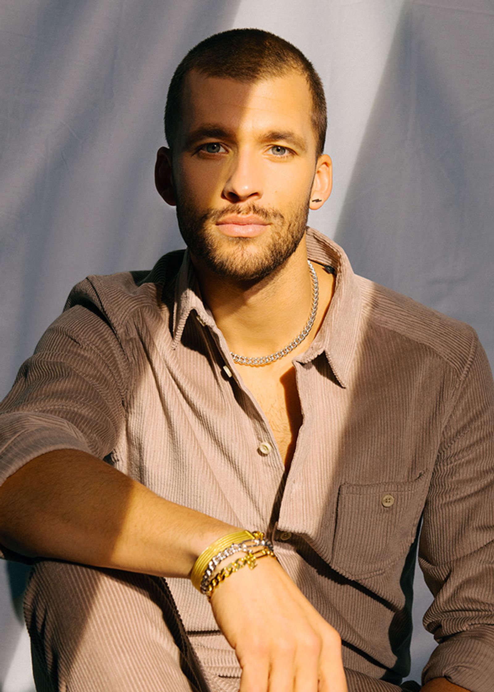 a man in a tan shirt sitting on a chair