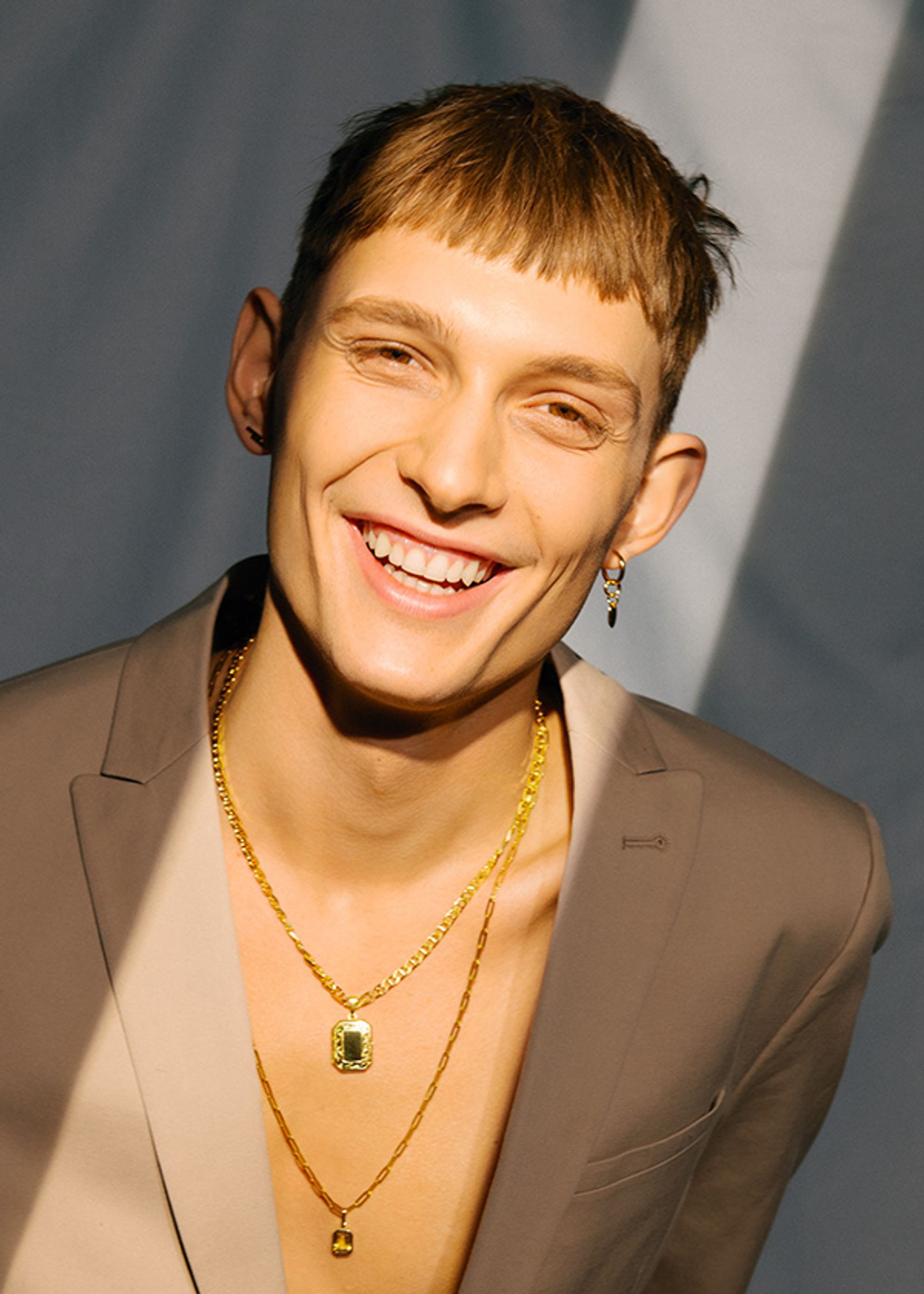 a young man in a suit with gold necklaces
