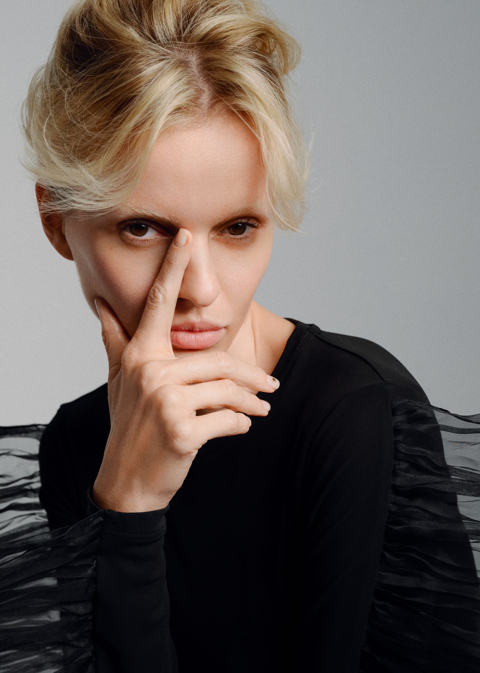 a blonde woman with her finger on her nose