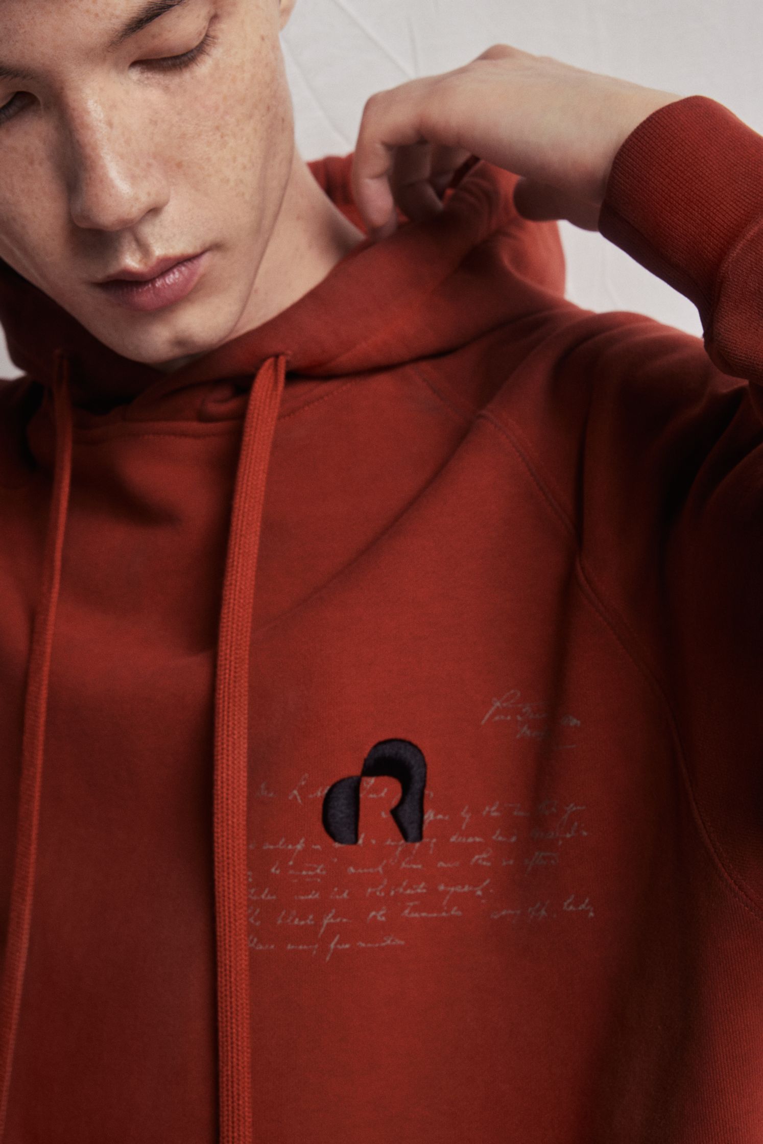 a man wearing a red hoodie with writing on it