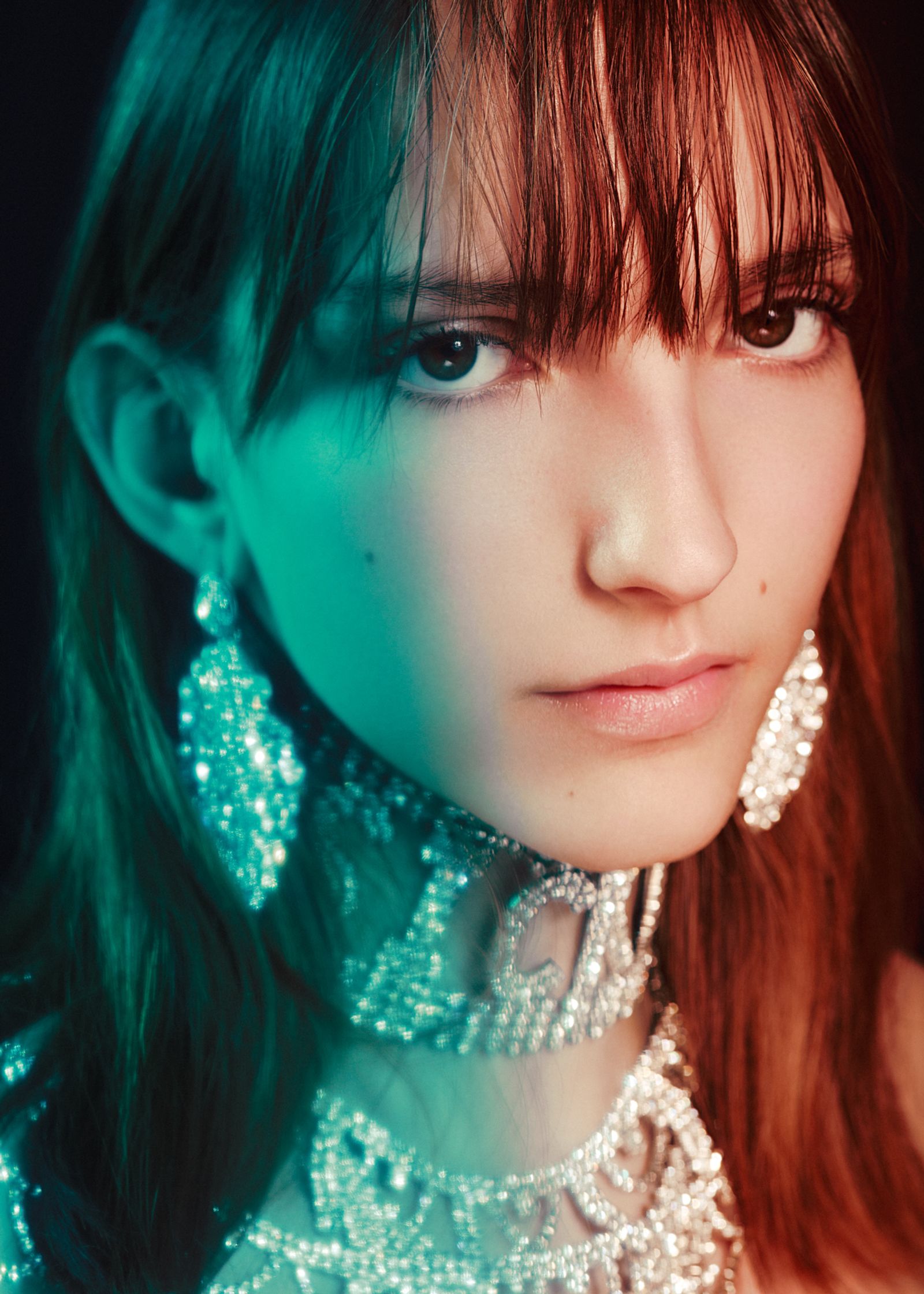 a woman with a necklace and earrings posing in front of a black background