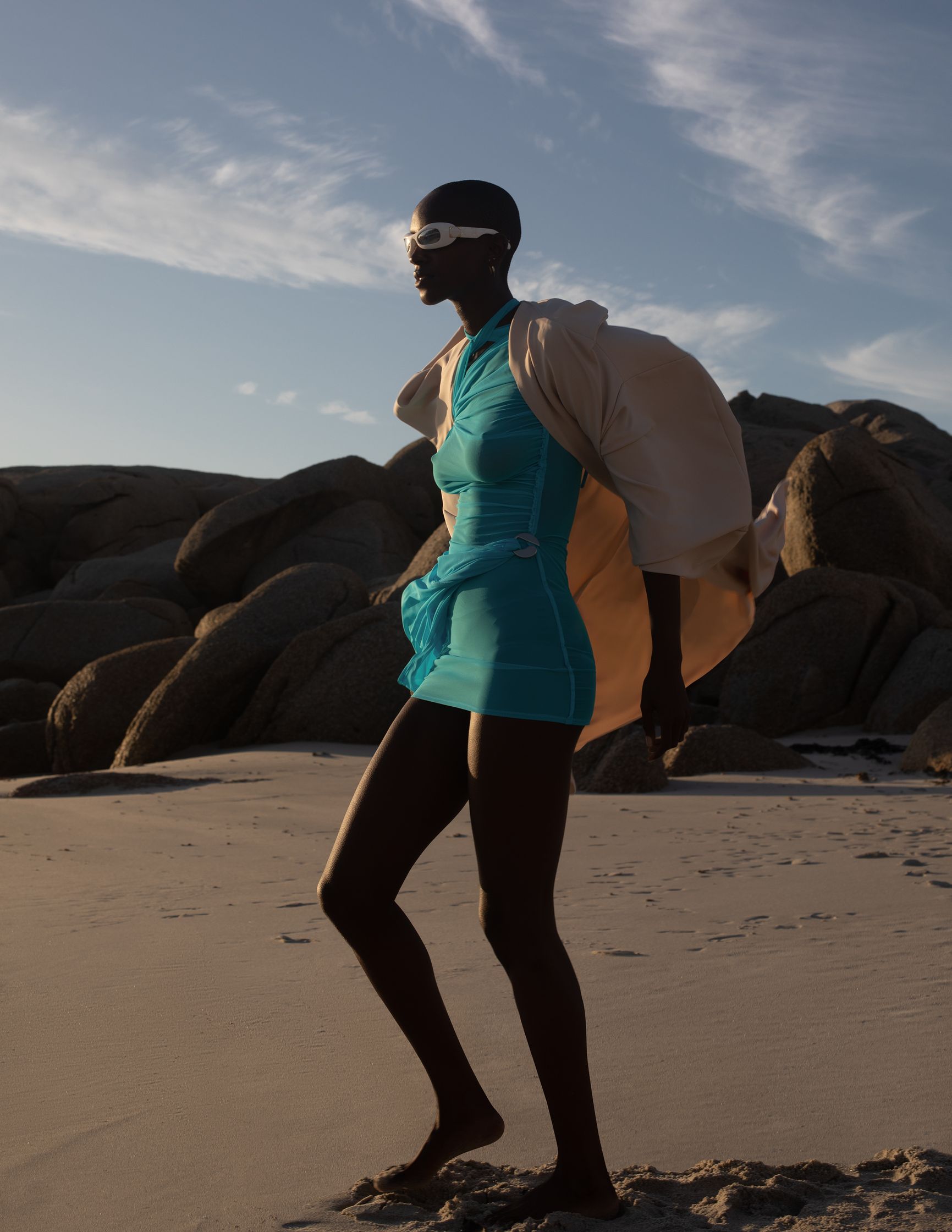 a woman in a blue dress walking on the beach