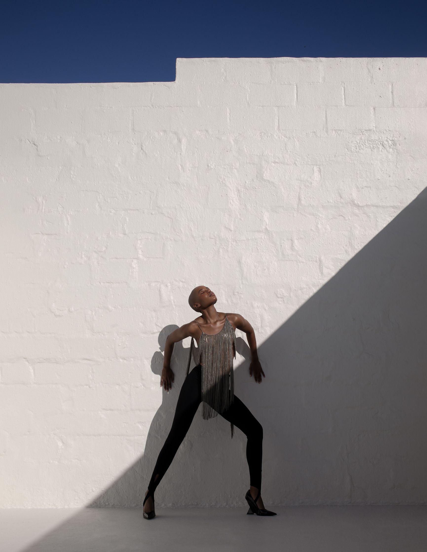 a dancer leaning against a white wall