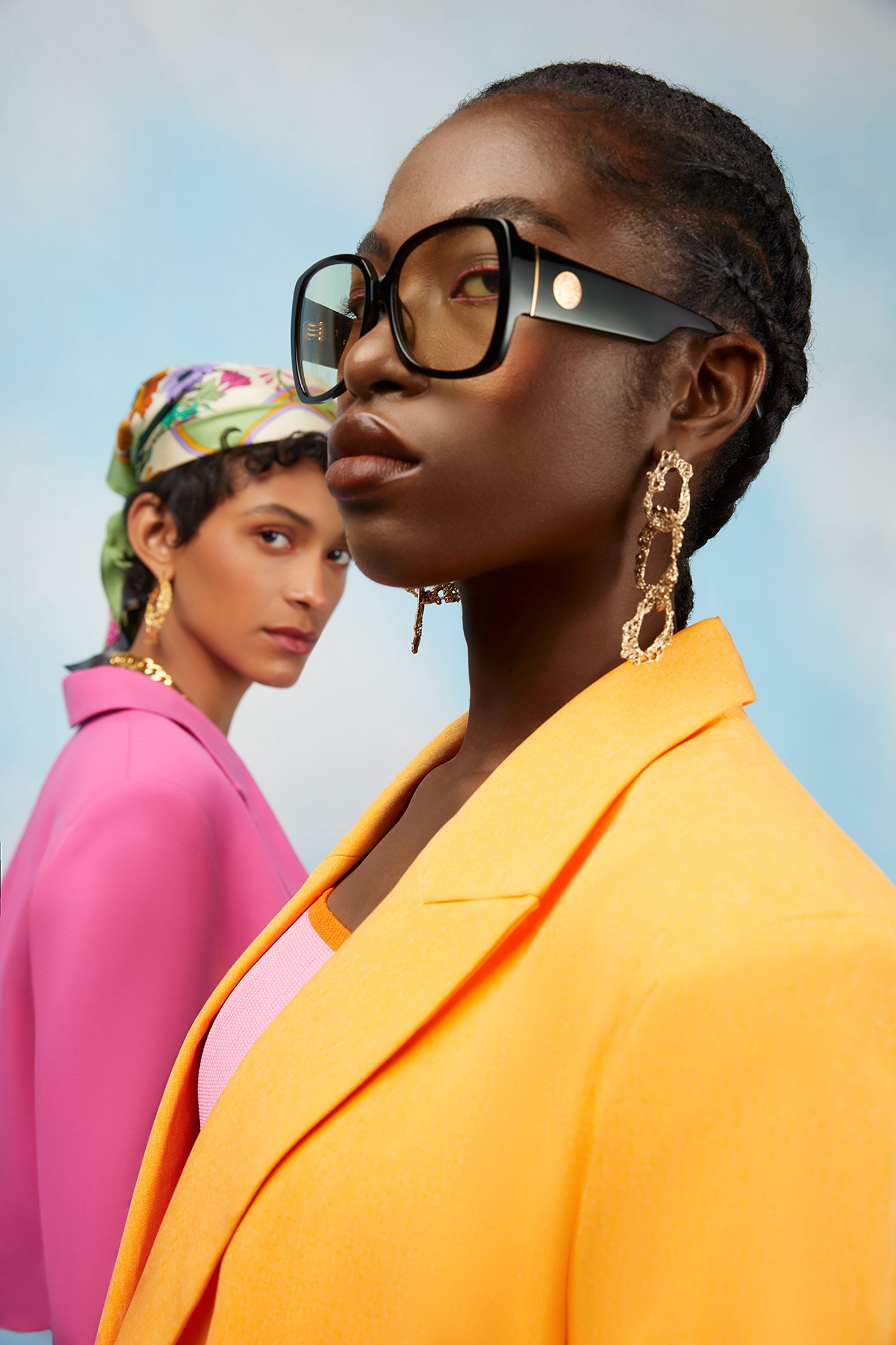two black women wearing glasses and a brightly colored jacket
