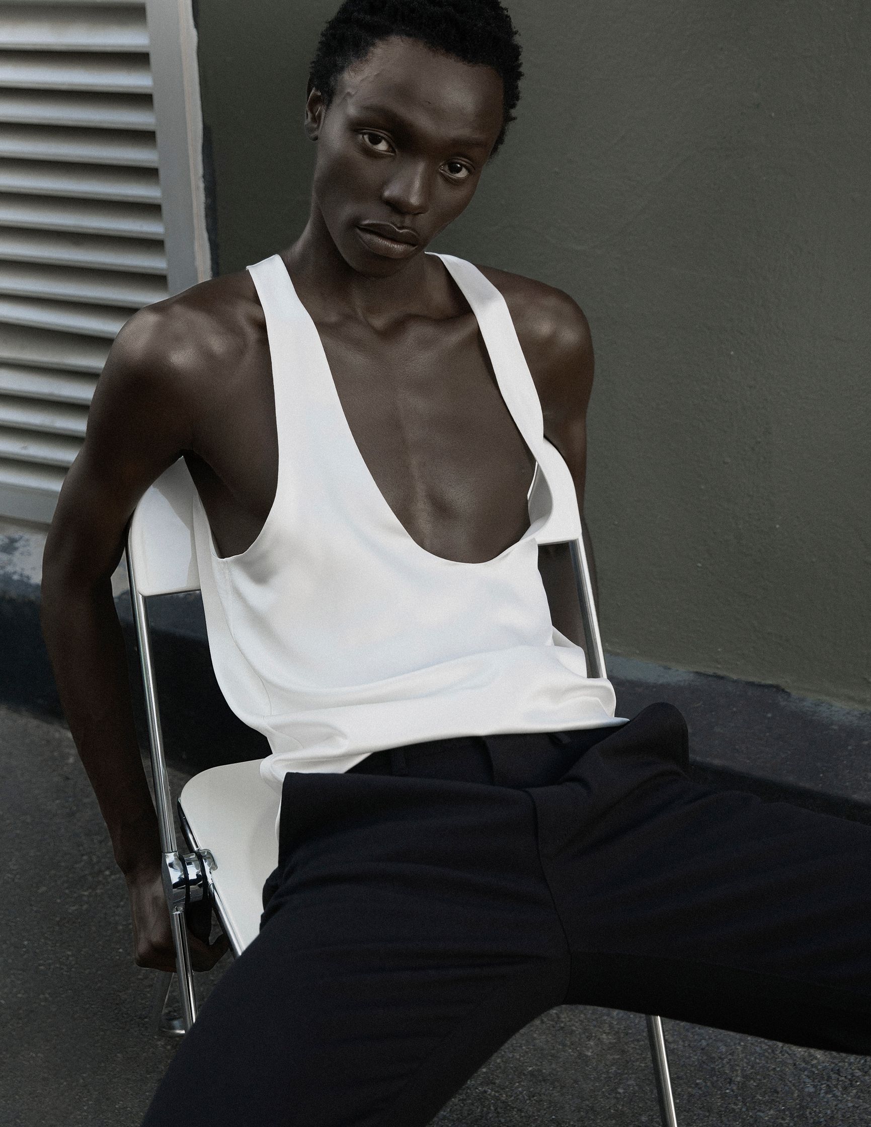 a man in a white tank top sitting on a chair