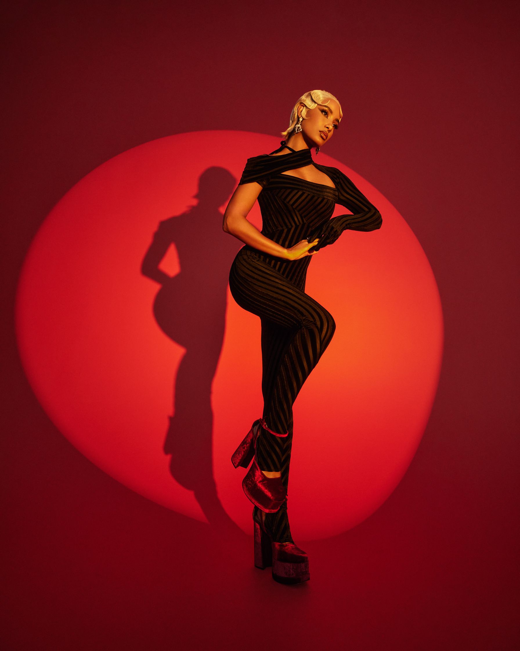 a woman posing in front of a red background