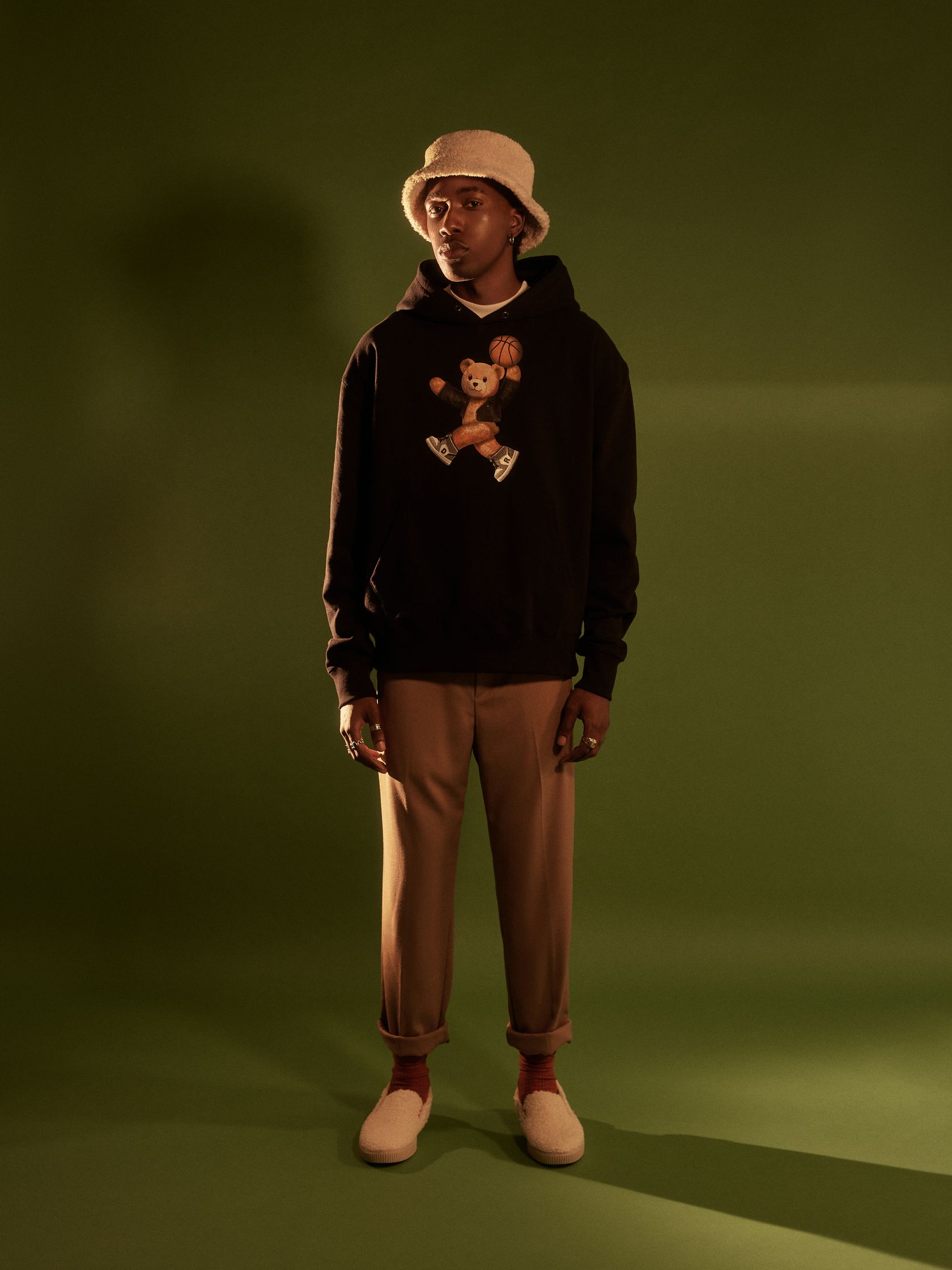a man in a black hoodie standing in front of a green background