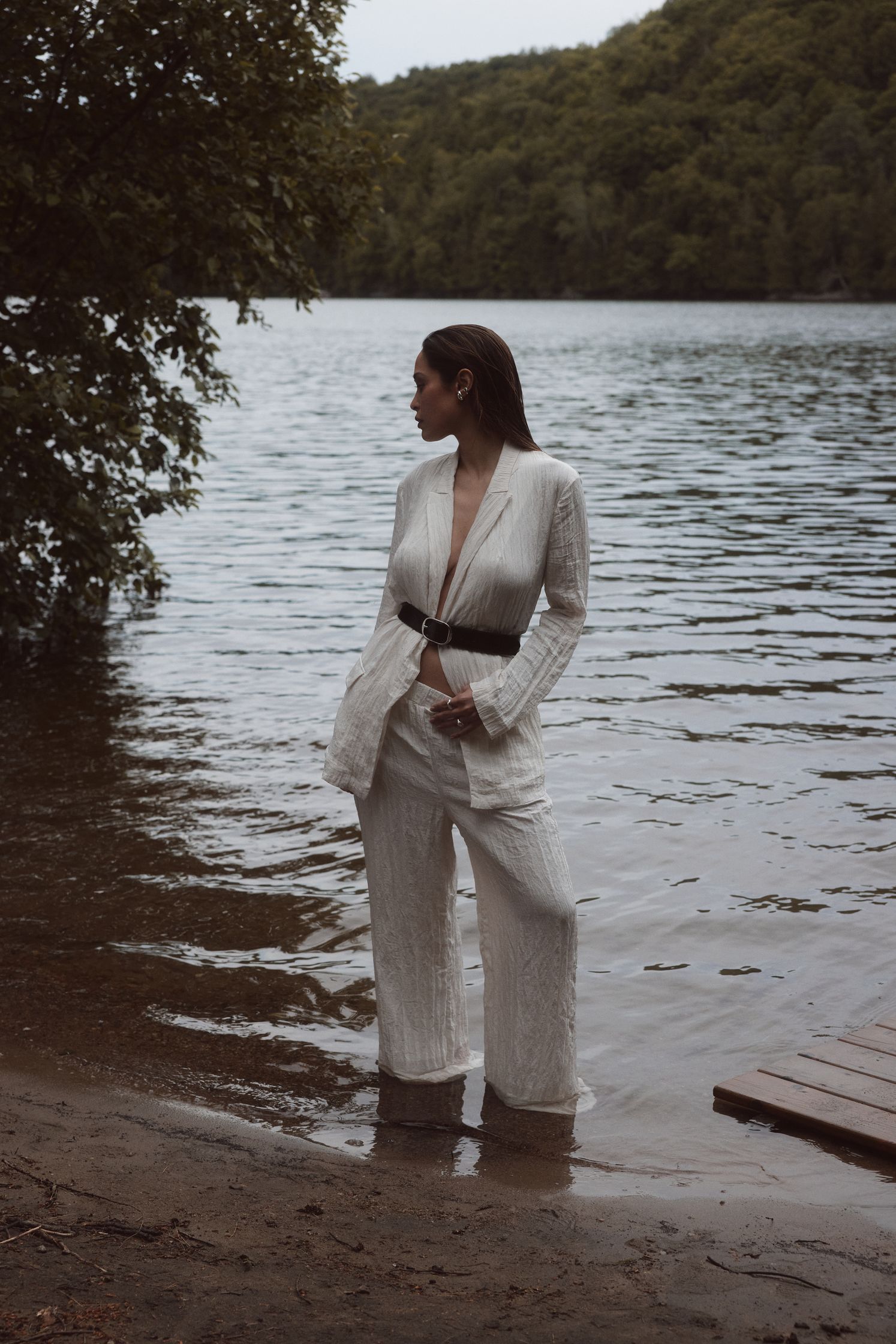 a woman in a white suit standing near a body of water