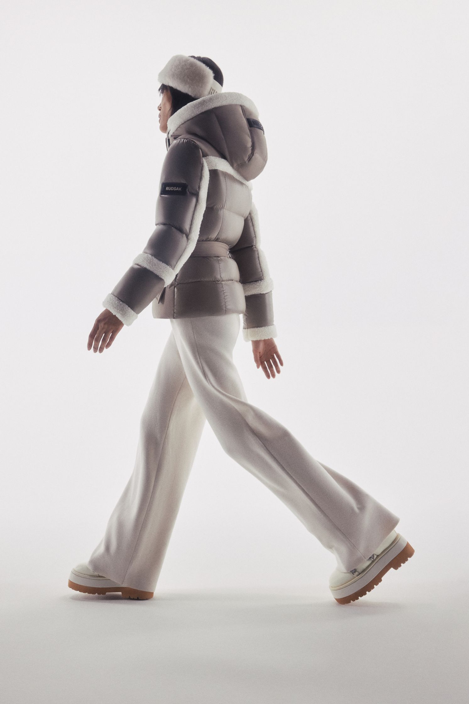 a woman is walking in a white jacket and white pants