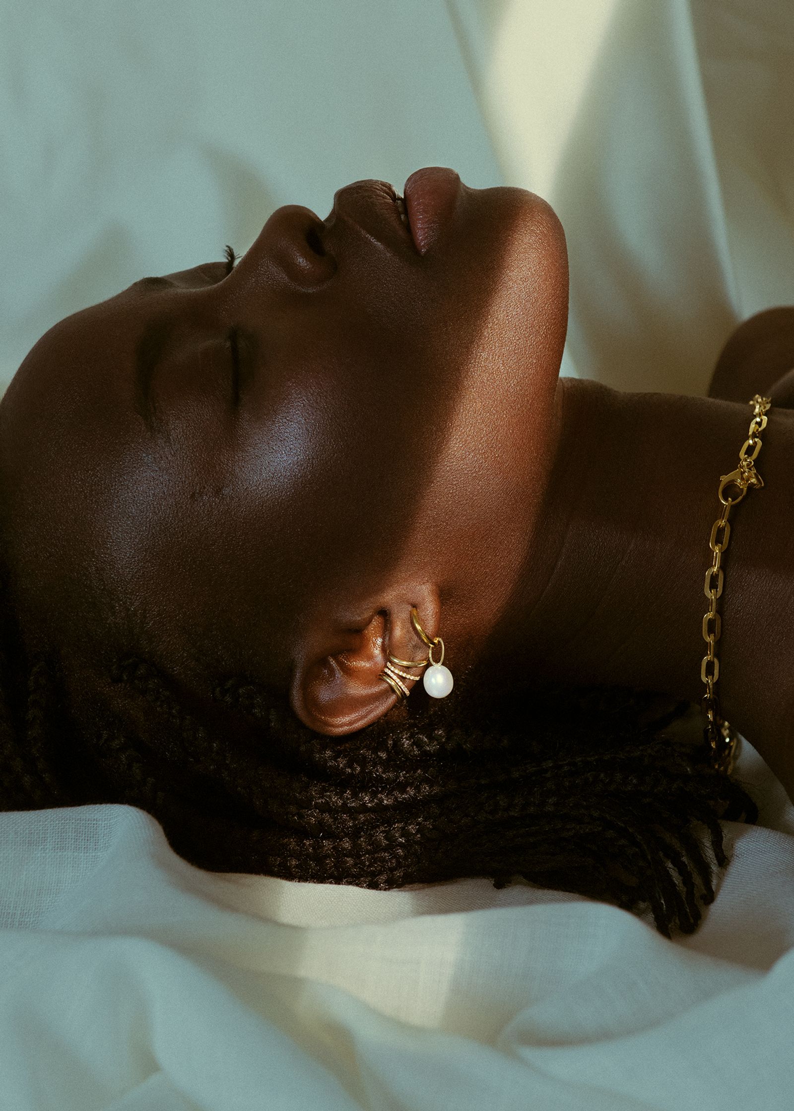 a black woman laying on a bed with gold earrings