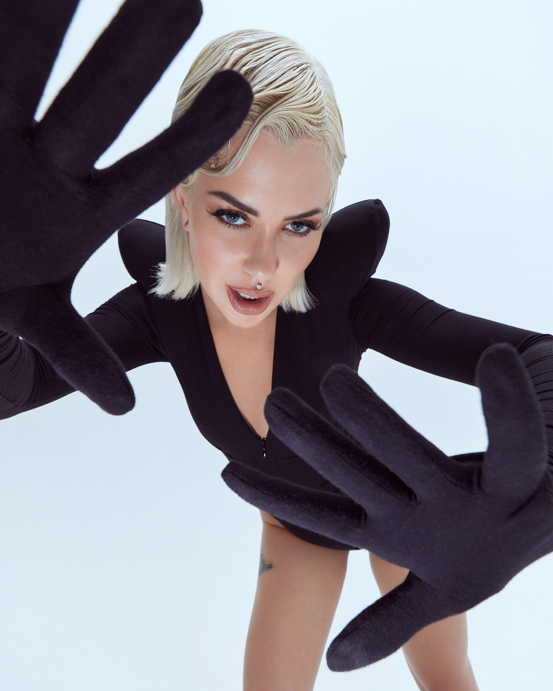 a woman in a black outfit with black gloves