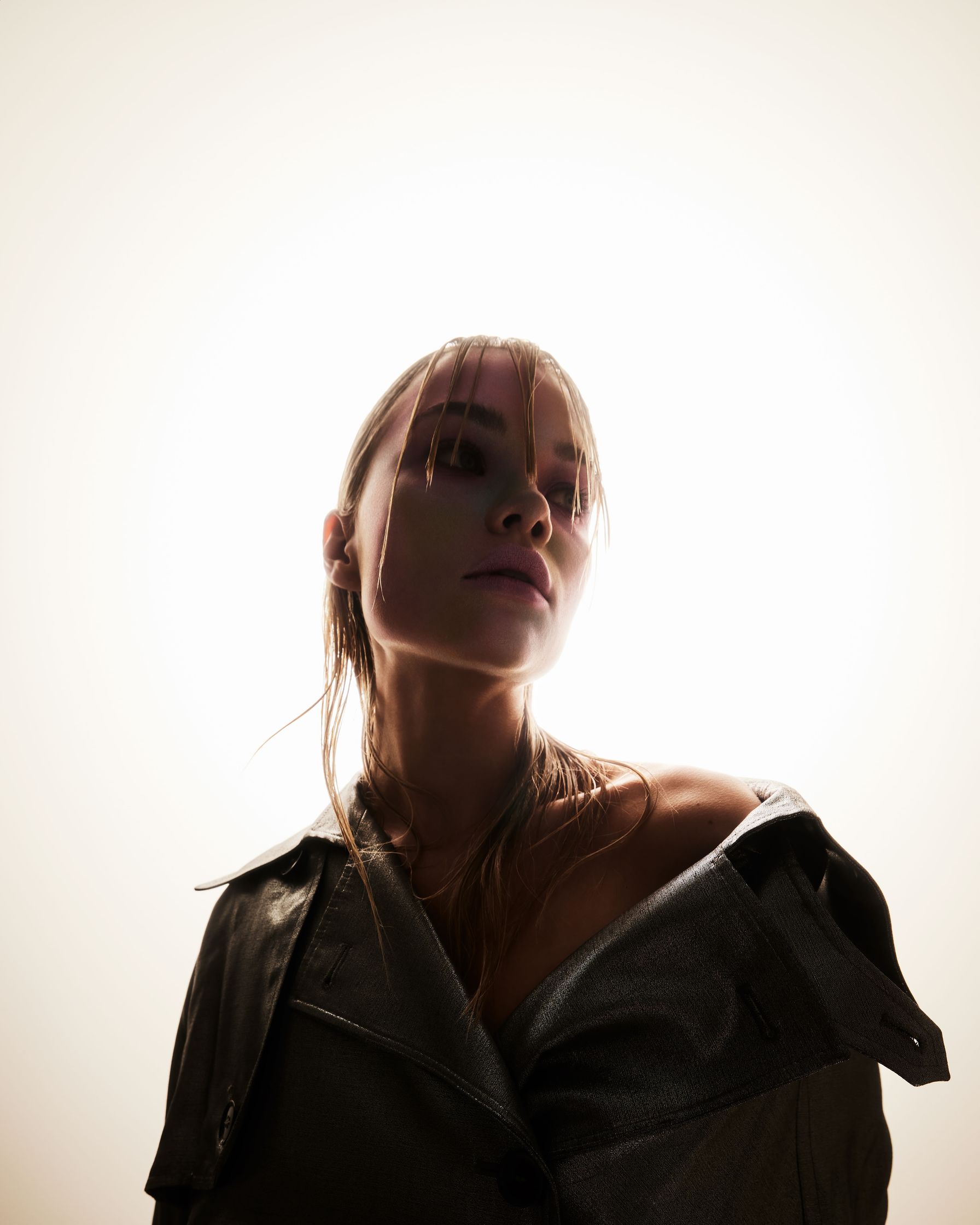 a woman in a leather jacket is looking up at the sun