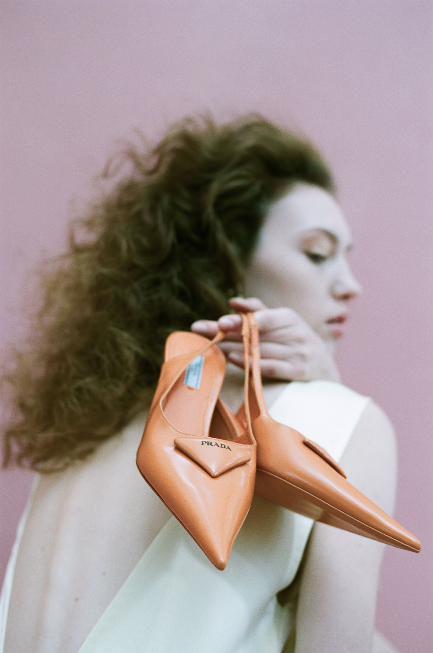 a woman is holding a pair of orange shoes