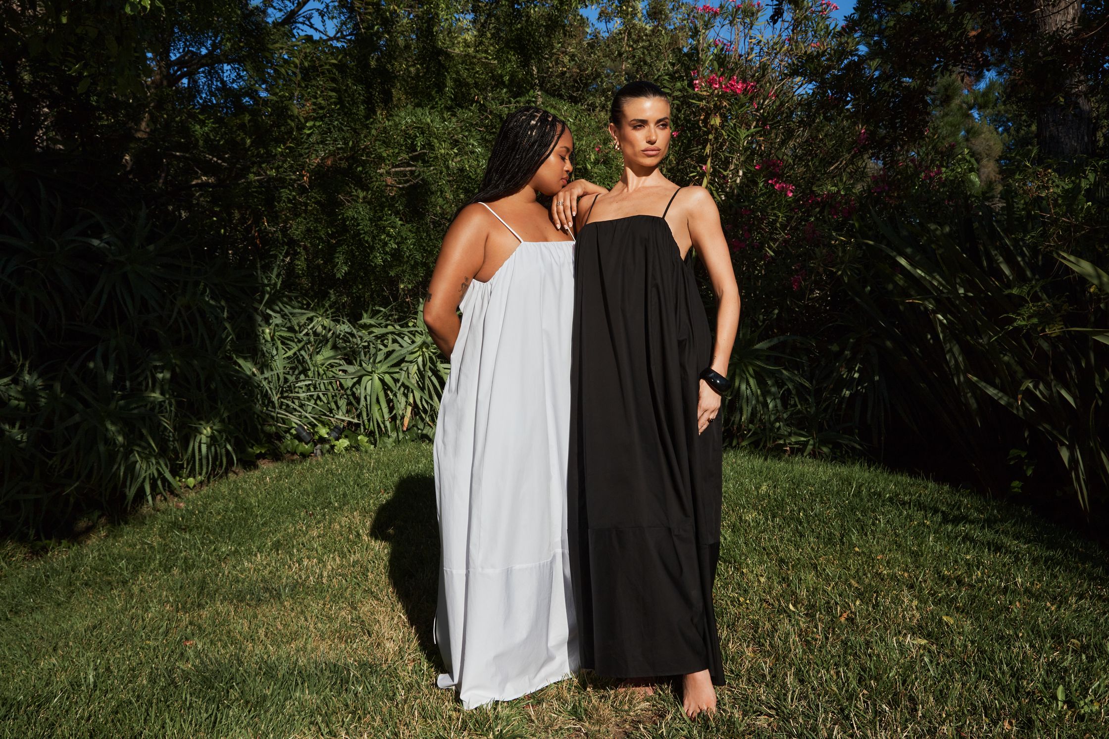 two women in black and white dresses standing in a grassy area