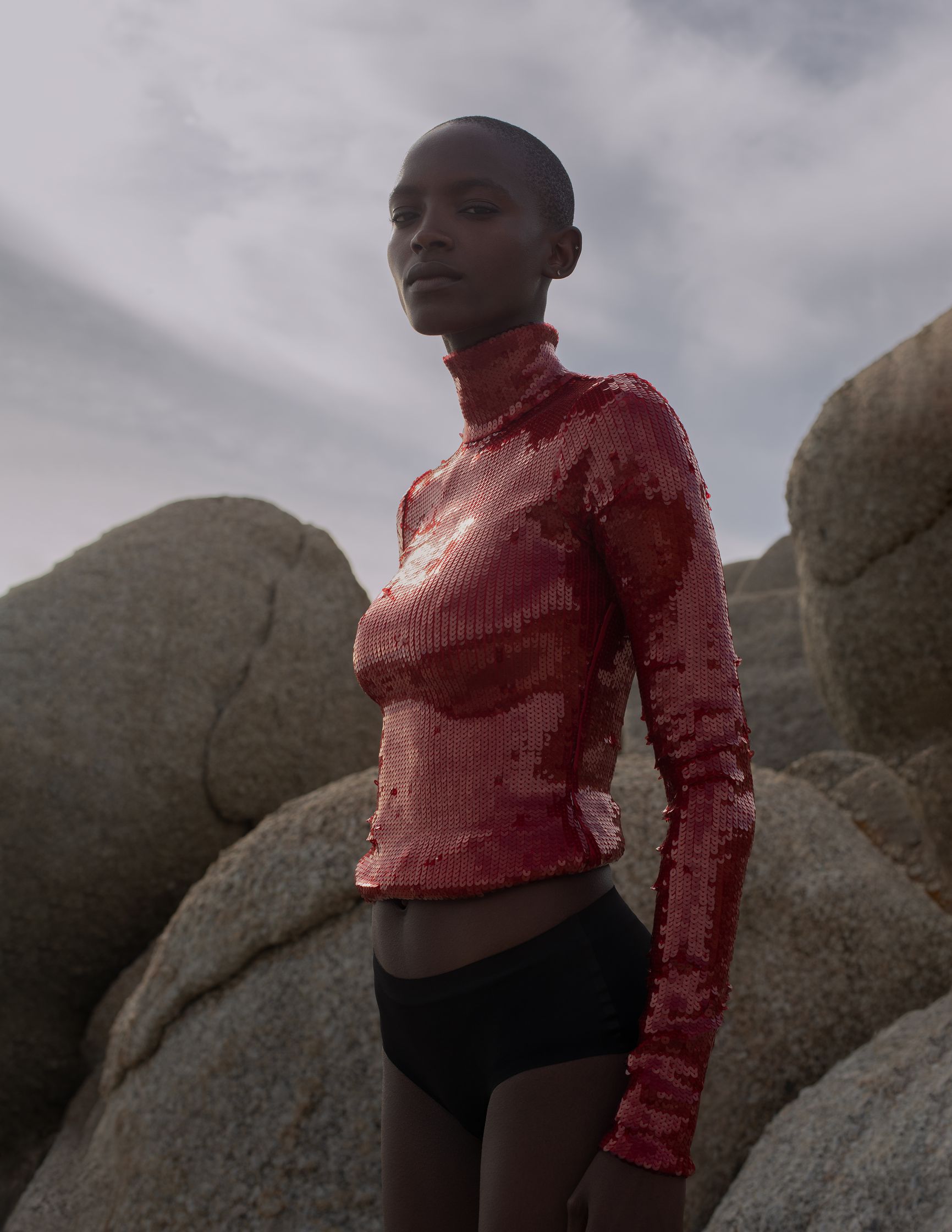 a woman in a red top standing on rocks