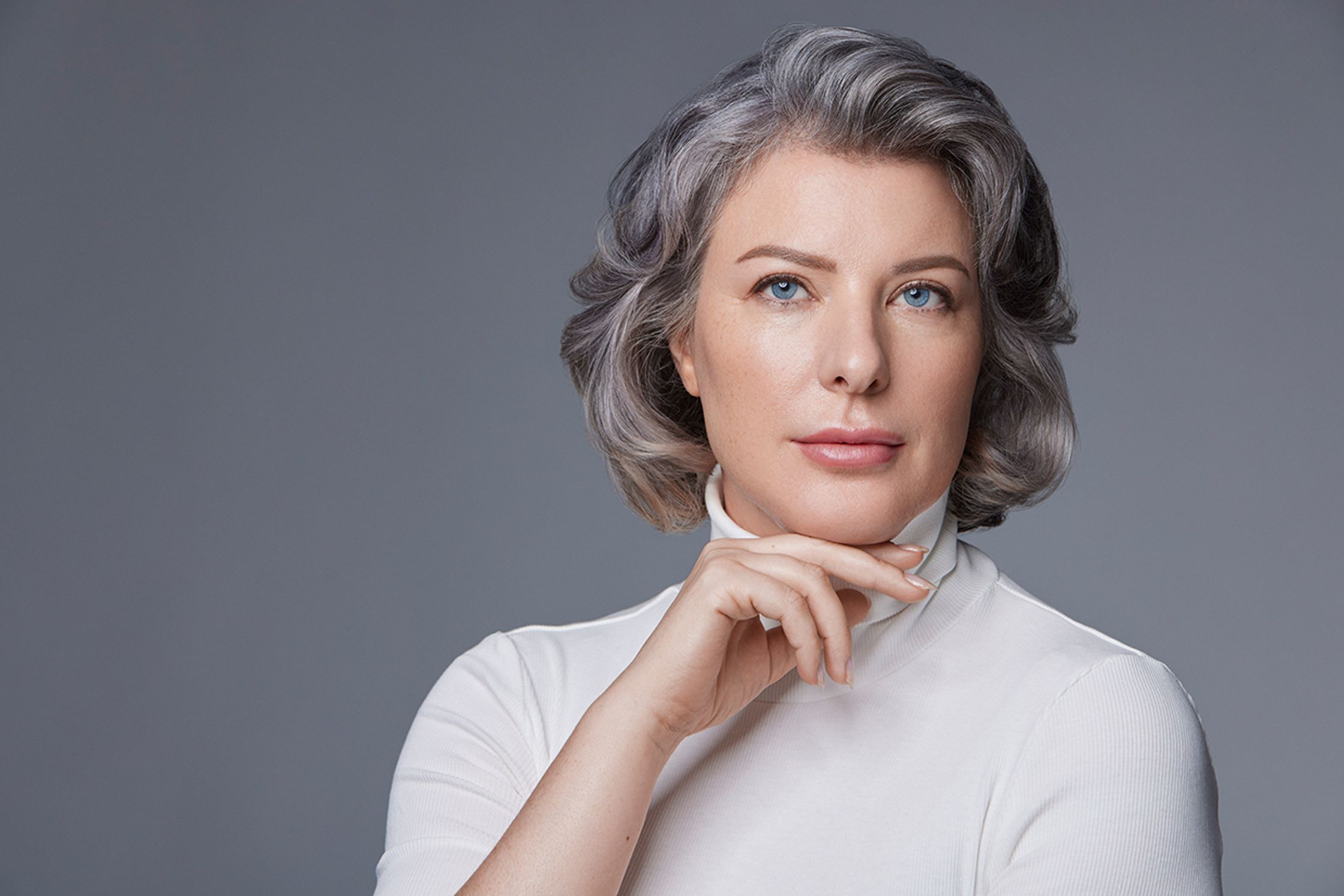 a woman with gray hair posing with her hand on her chin
