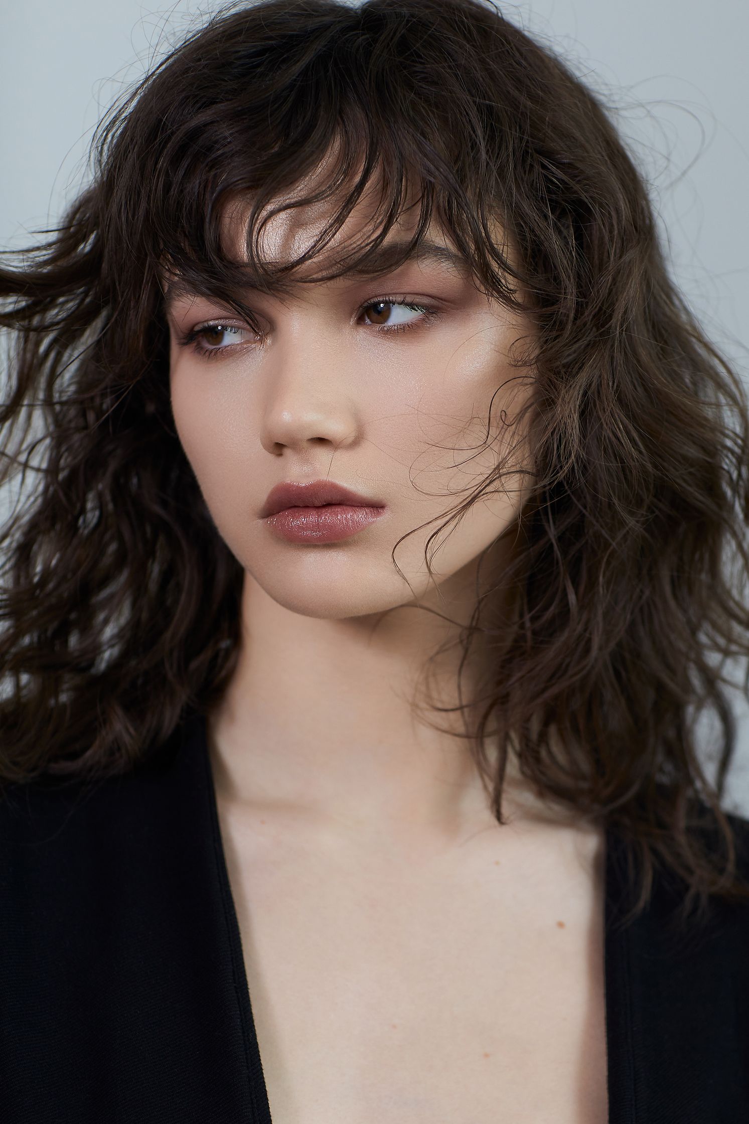 a model wearing a black top and a long wavy hair