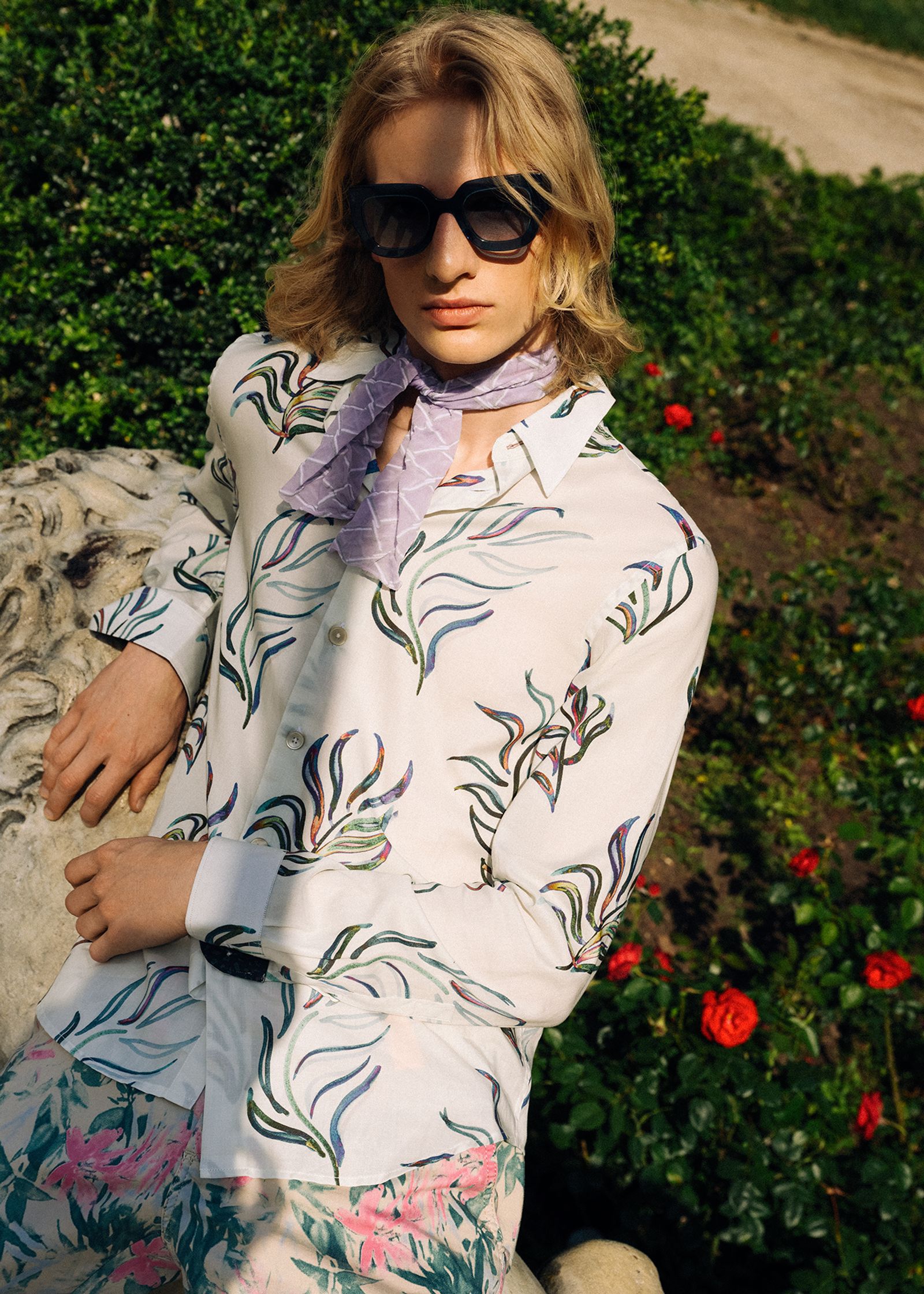 a young man wearing a floral shirt and sunglasses