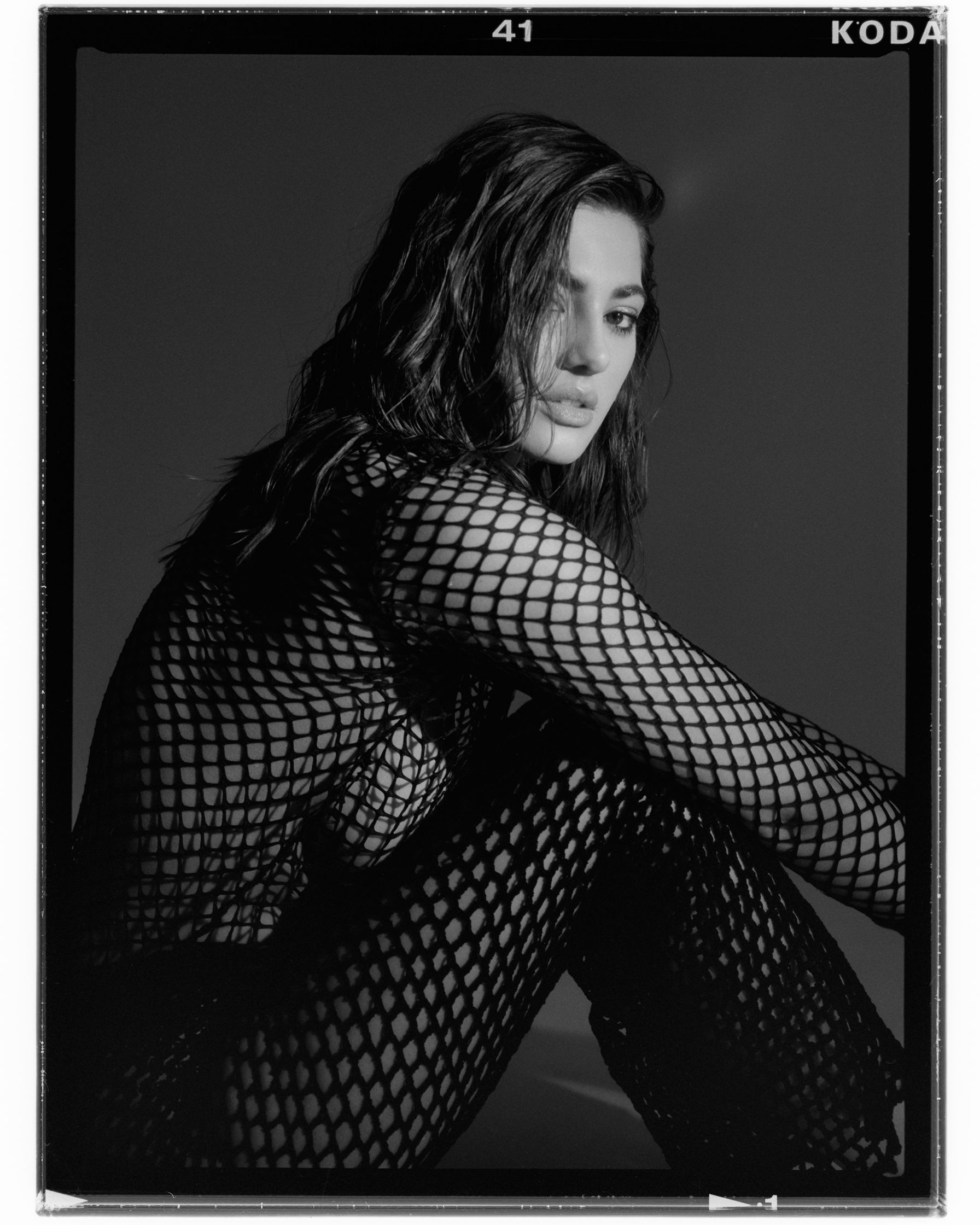 a black and white photo of a woman in fishnets