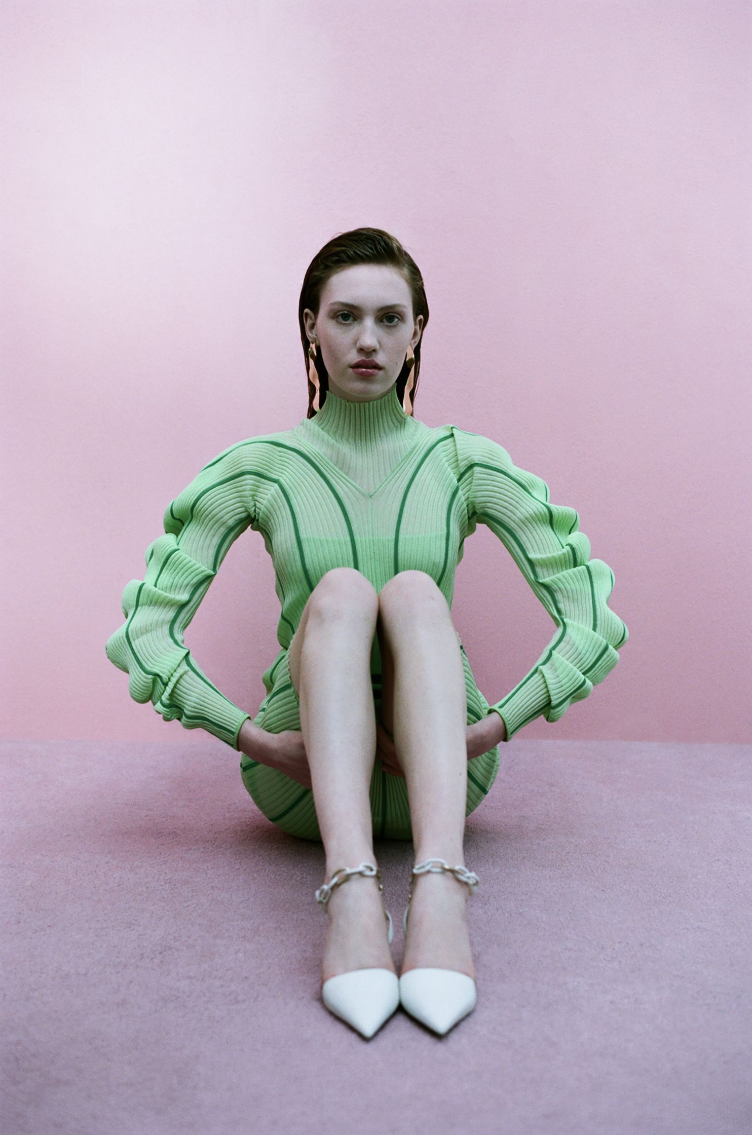 a woman in a green dress sitting on a pink floor