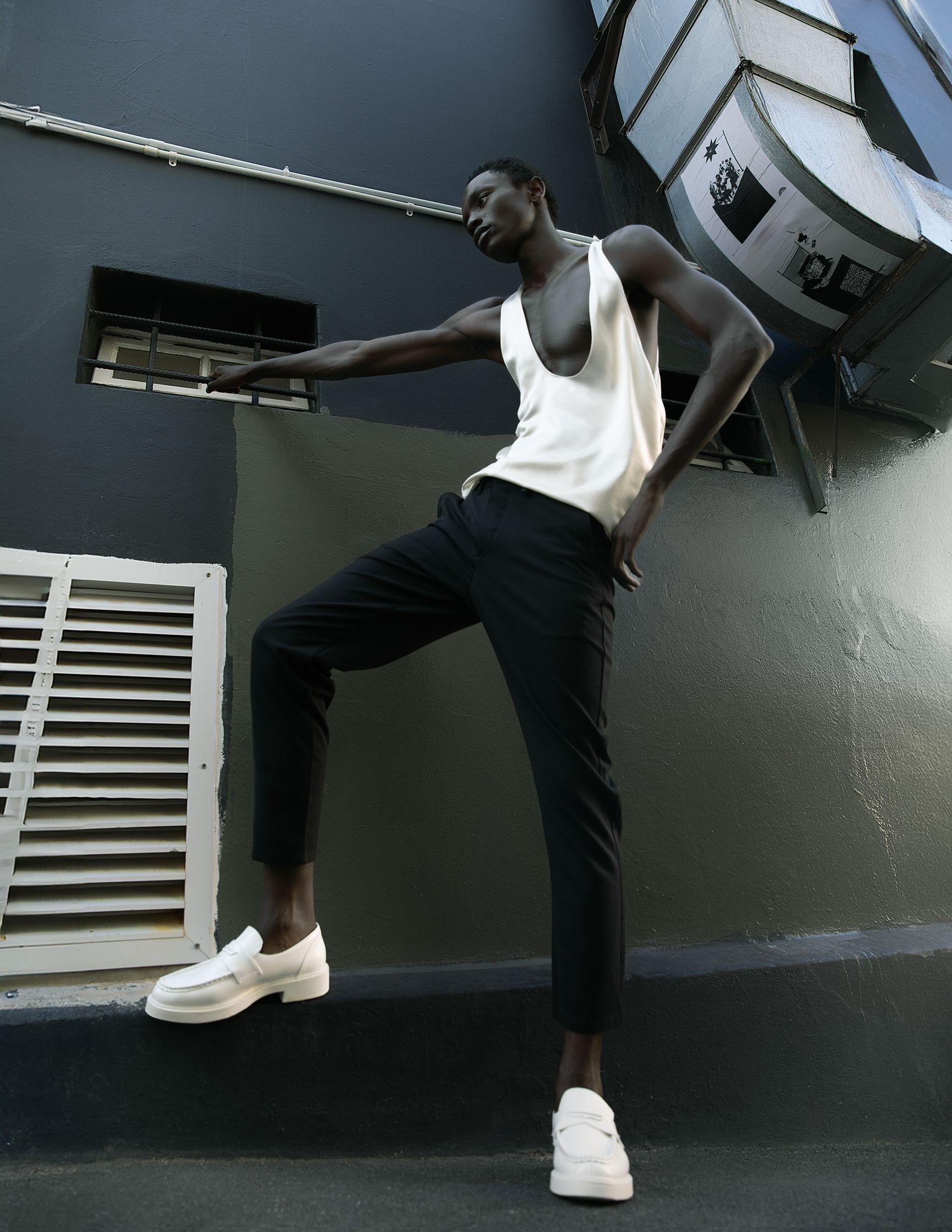 a man in a white tank top and white sneakers