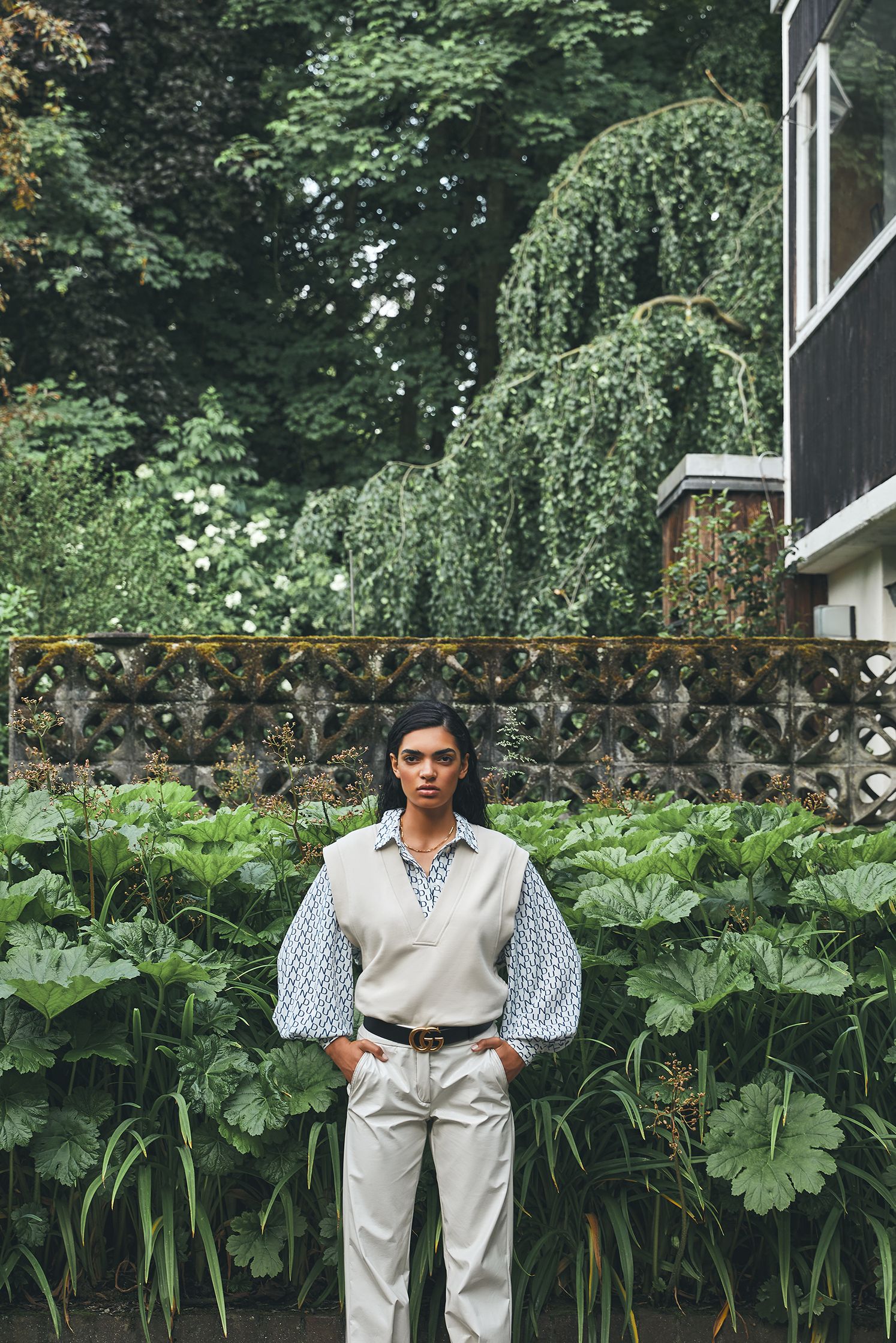 a woman standing in front of a house with plants