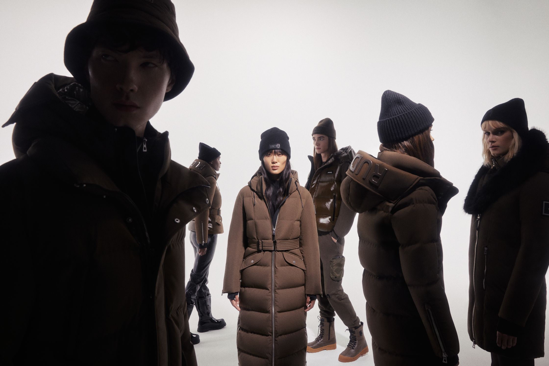 a group of people in brown coats standing in front of a white background
