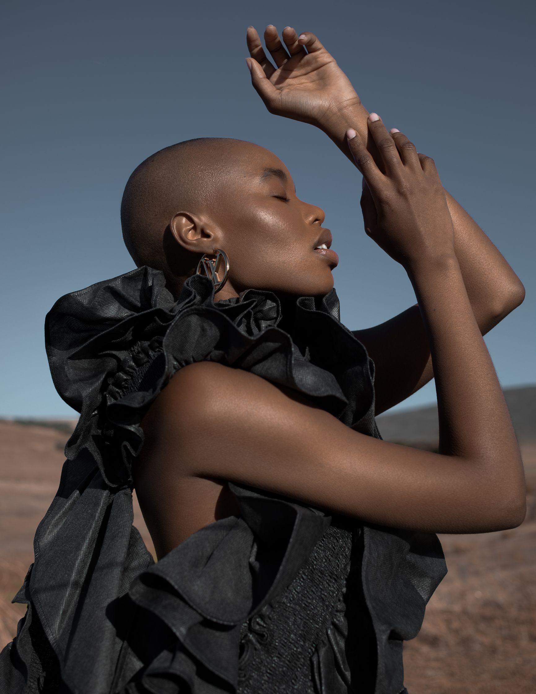a black woman in a black dress posing in the desert
