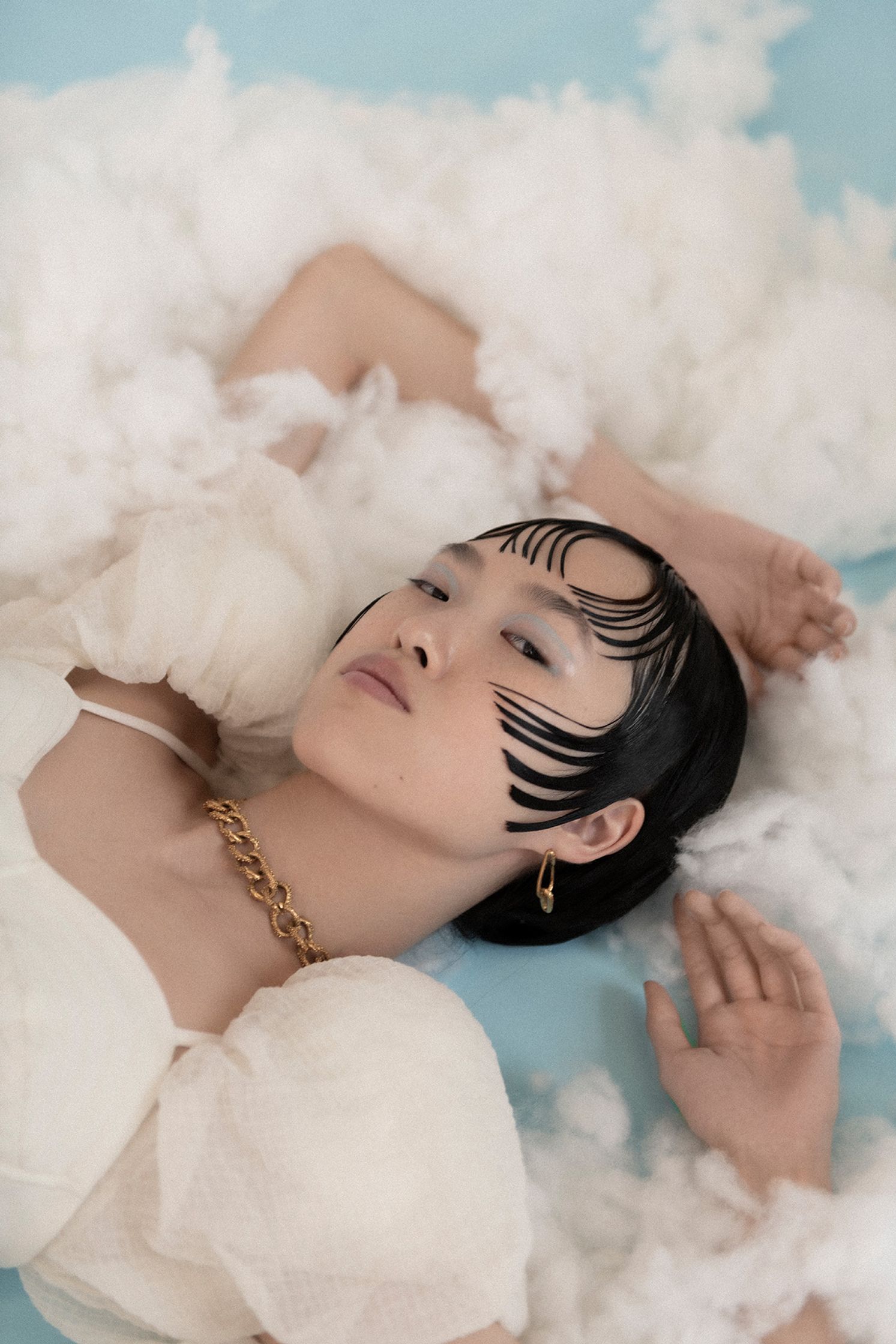 a woman laying on a bed of white clouds