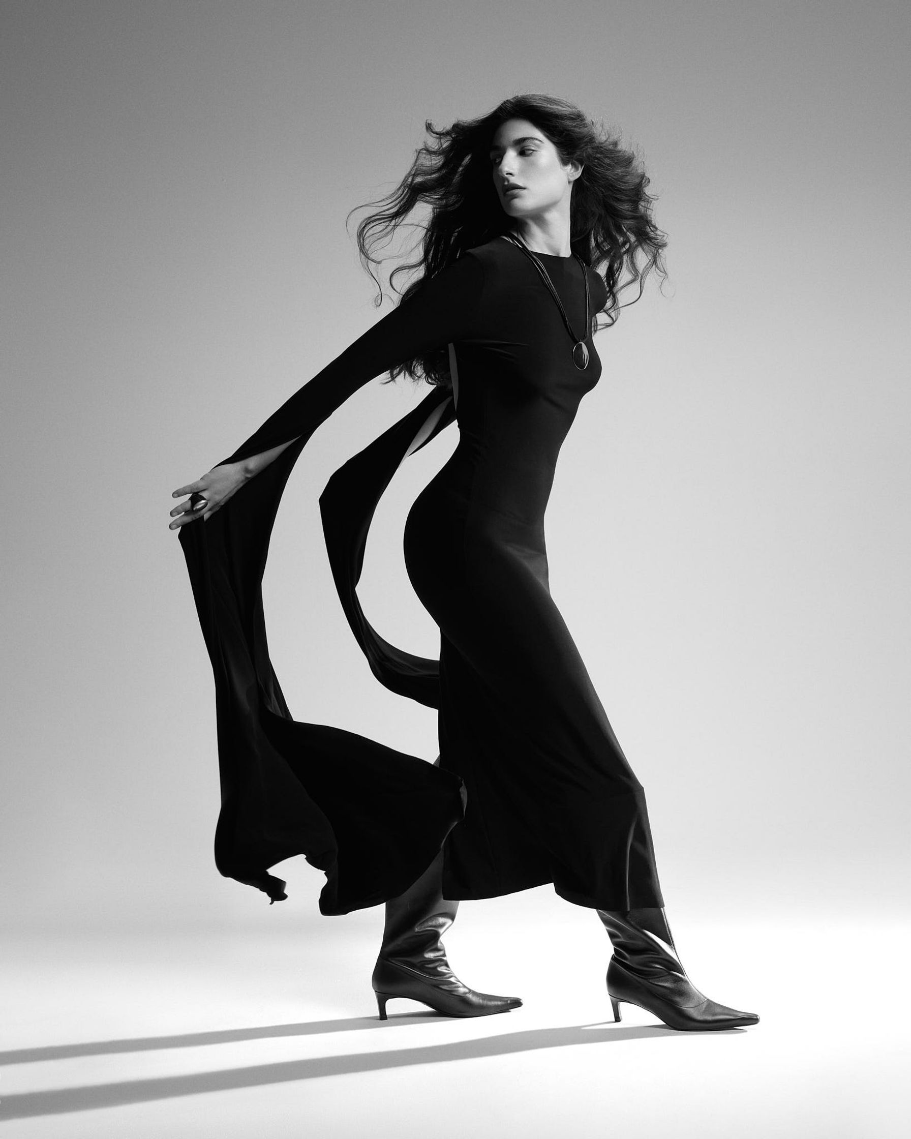 a black and white photo of a woman in a long black dress