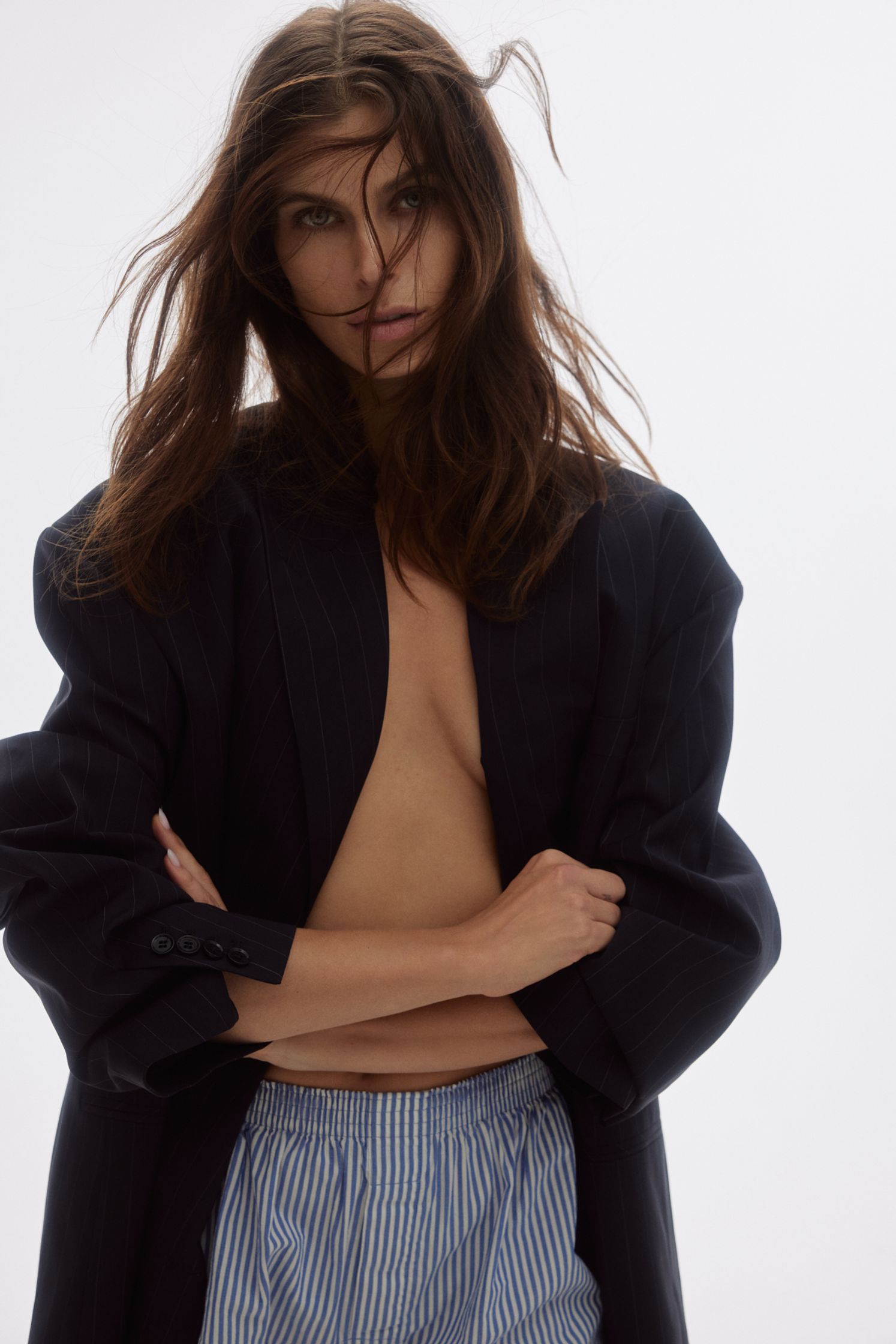 a woman in a blue jacket and striped shorts