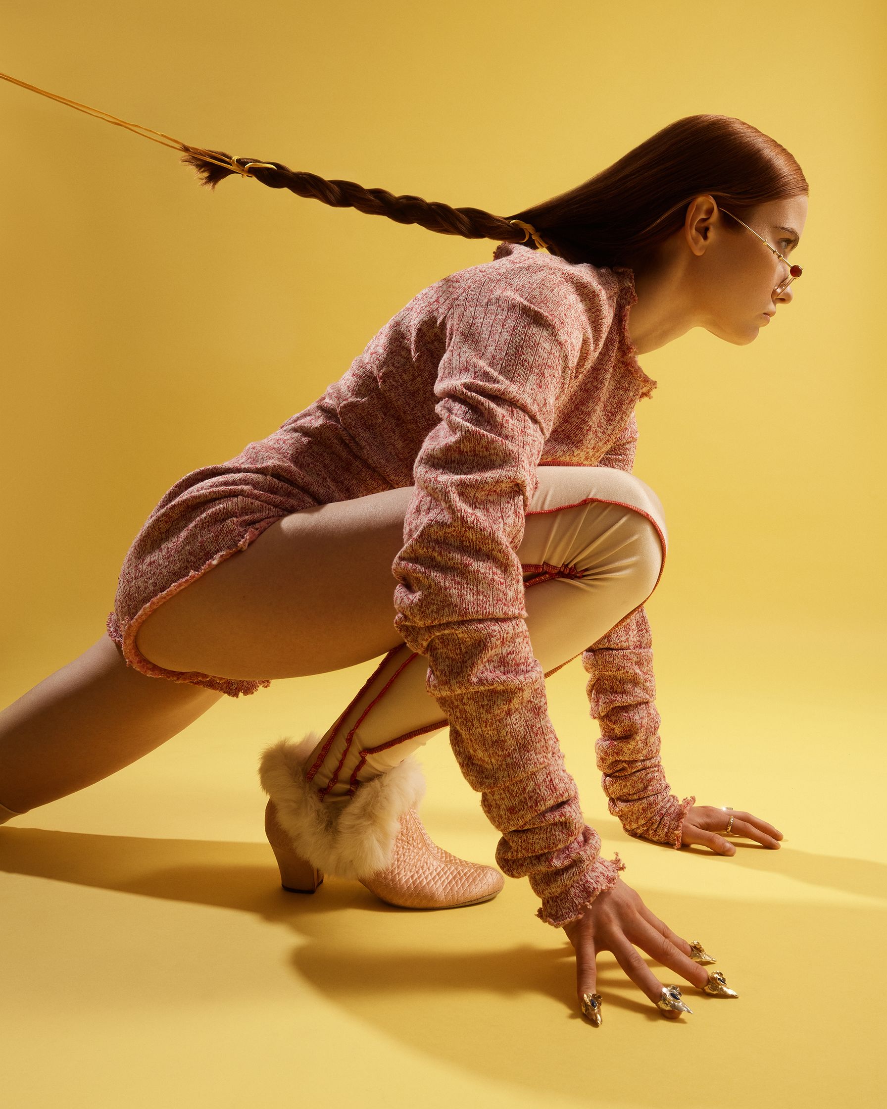 a woman with long hair crouching down on a yellow background
