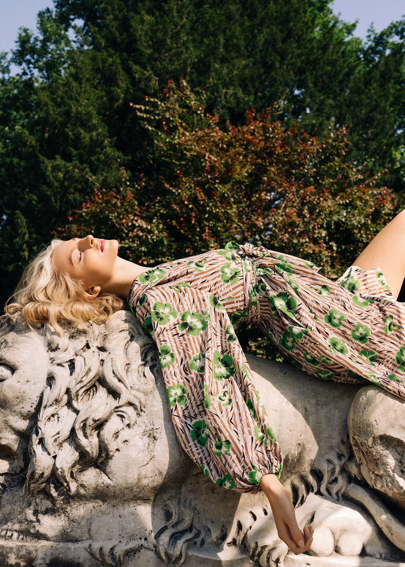 a woman laying on top of a statue of a lion