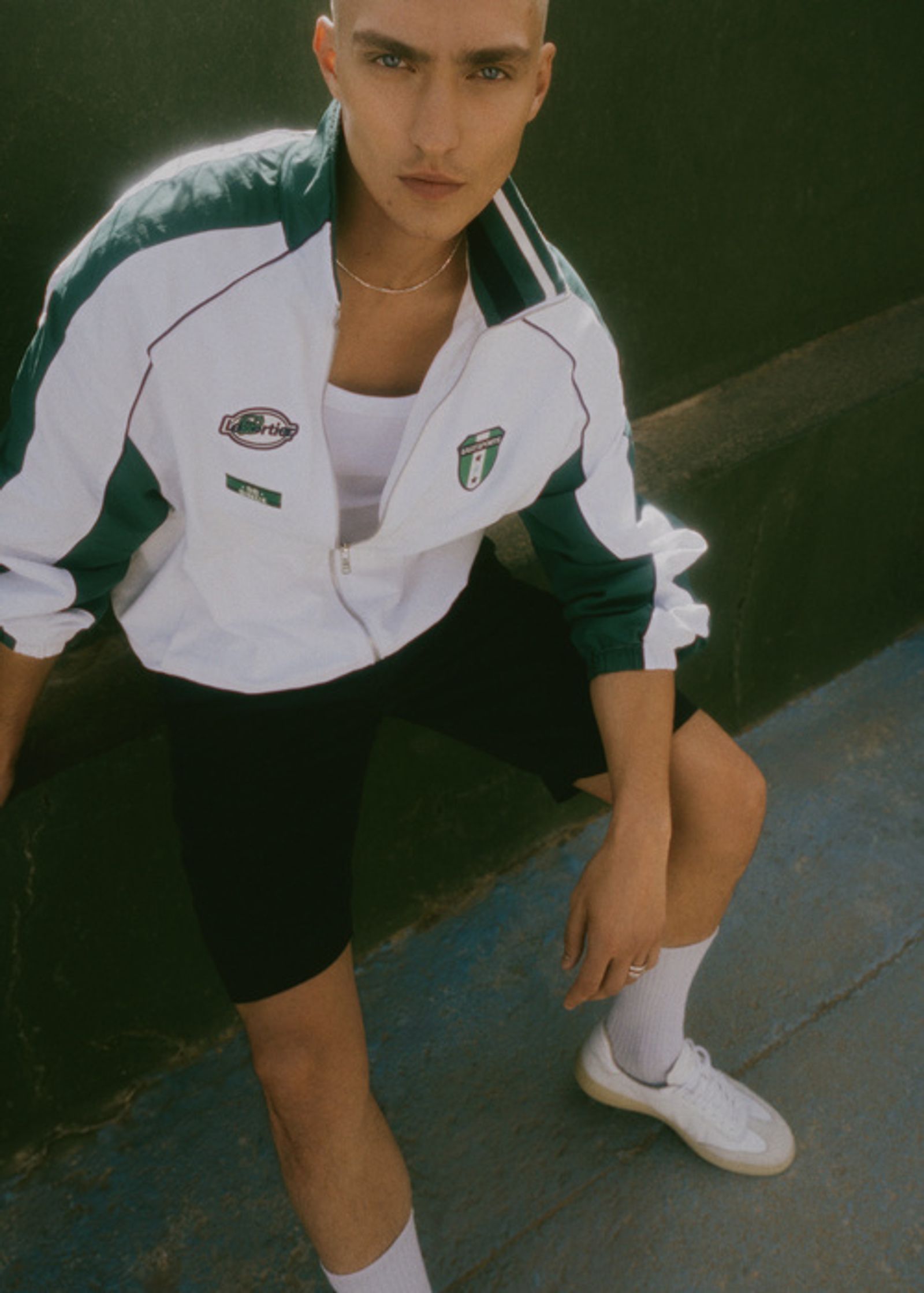 a young man wearing a white and green track jacket and shorts
