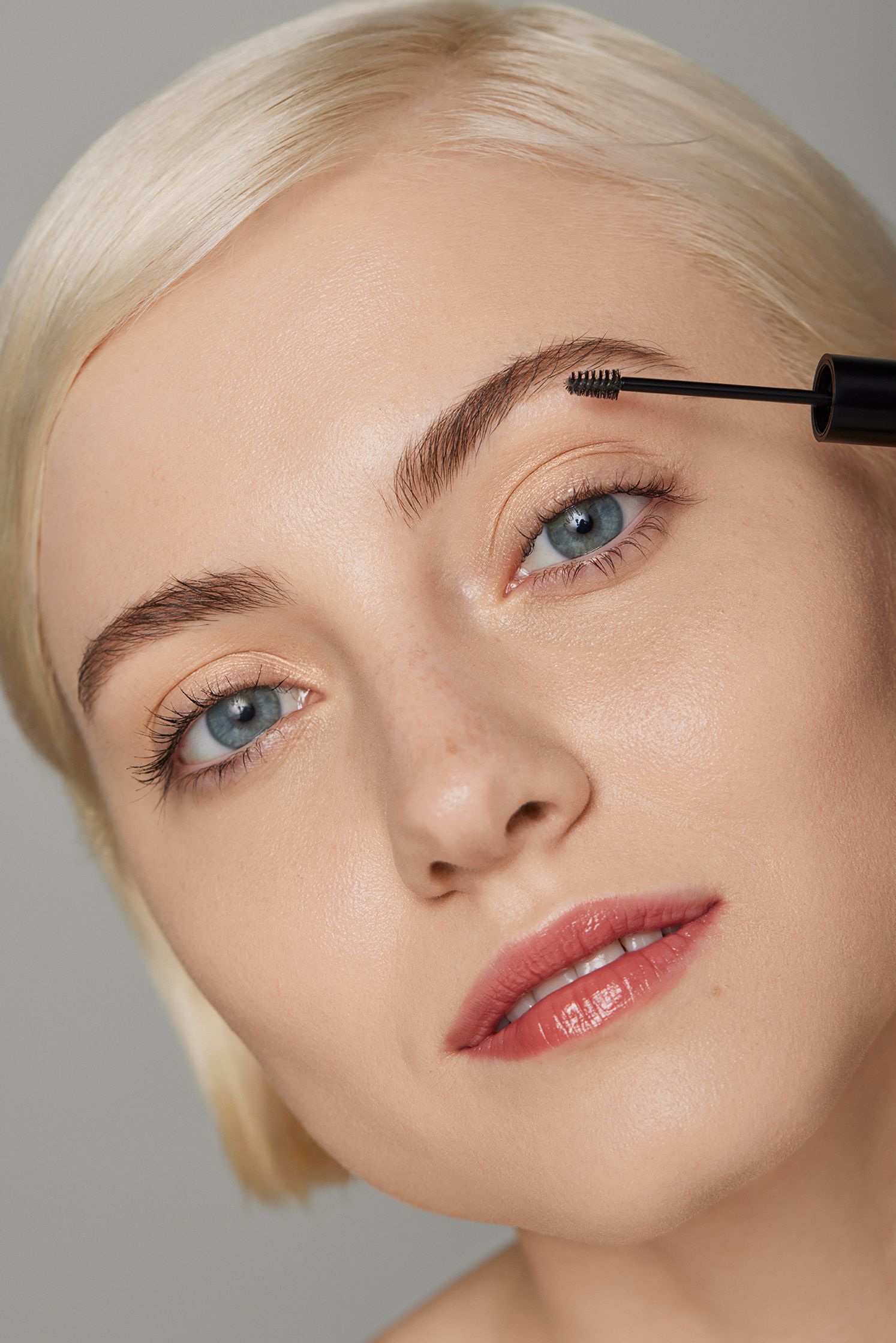 a woman is applying mascara to her eyebrows