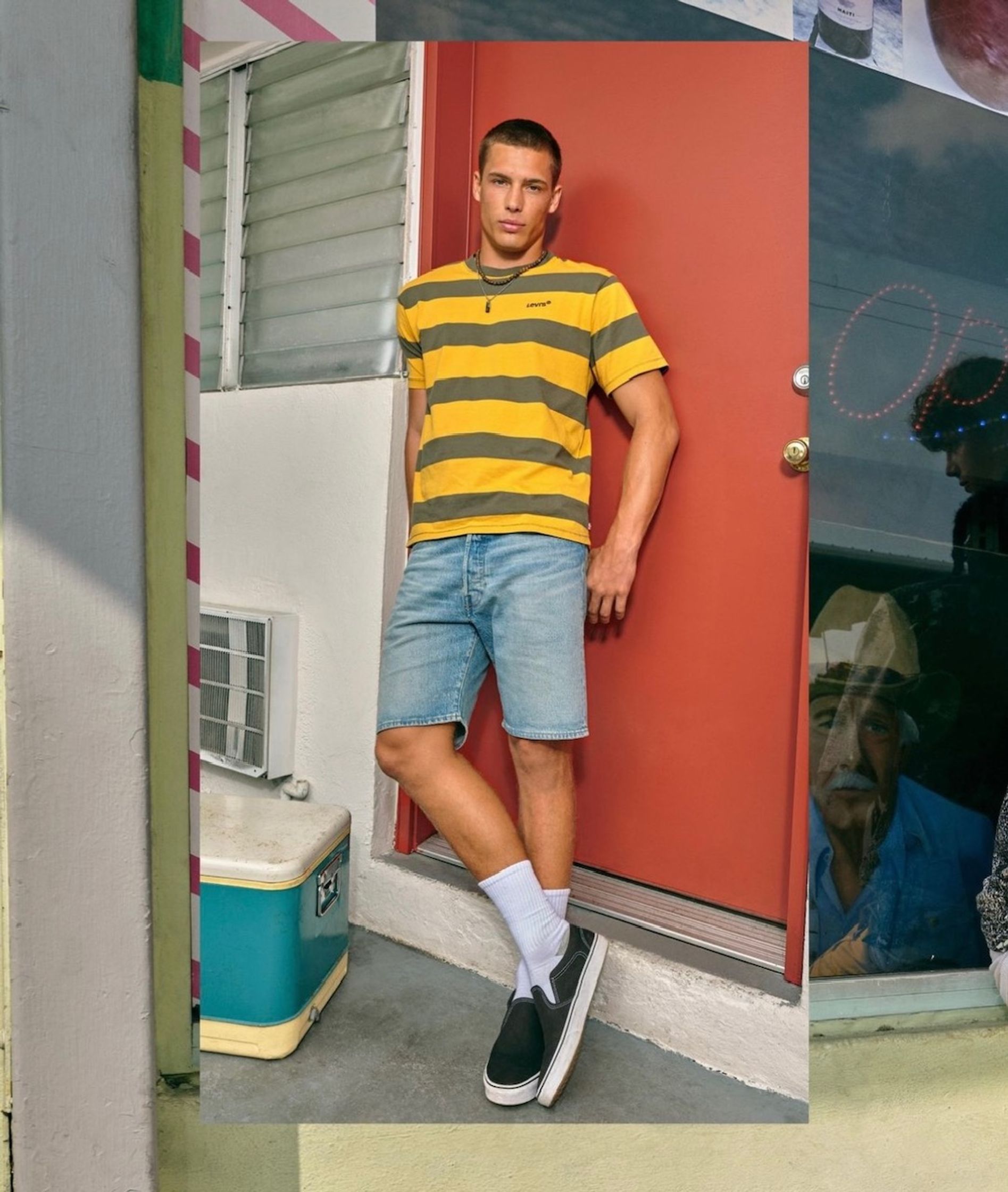 a man in a striped shirt and shorts leaning against a door usc uk