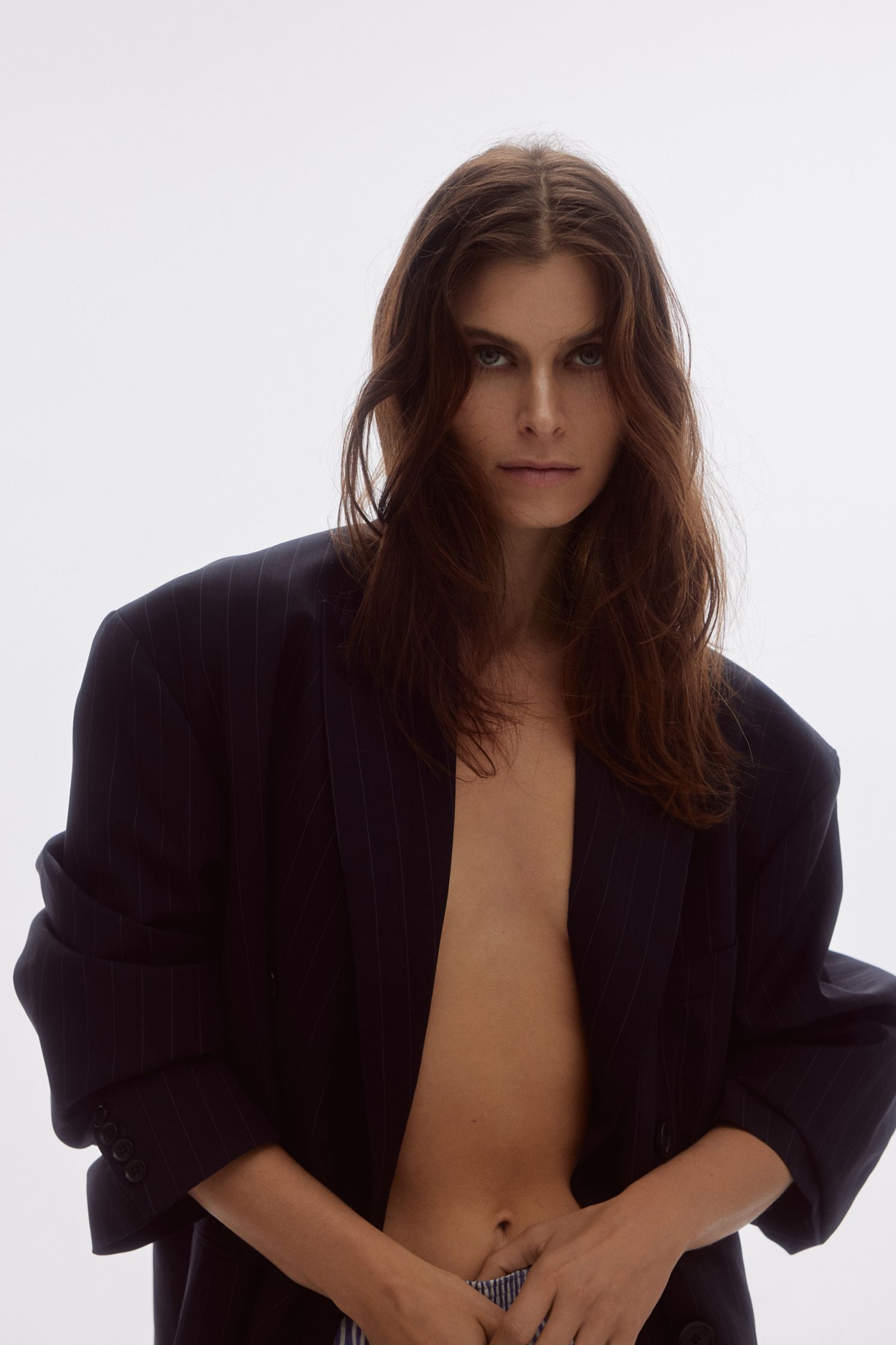 a woman in a blazer and jeans posing for a photo shoot