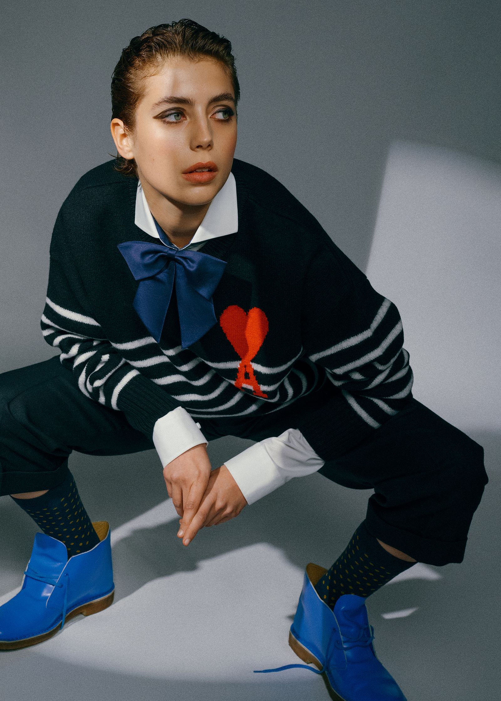a woman in a sweater and blue shoes crouching down