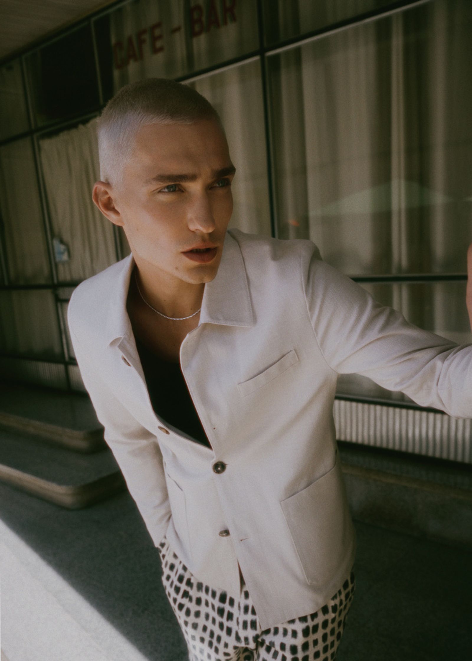 a man with a shaved head standing in front of a building
