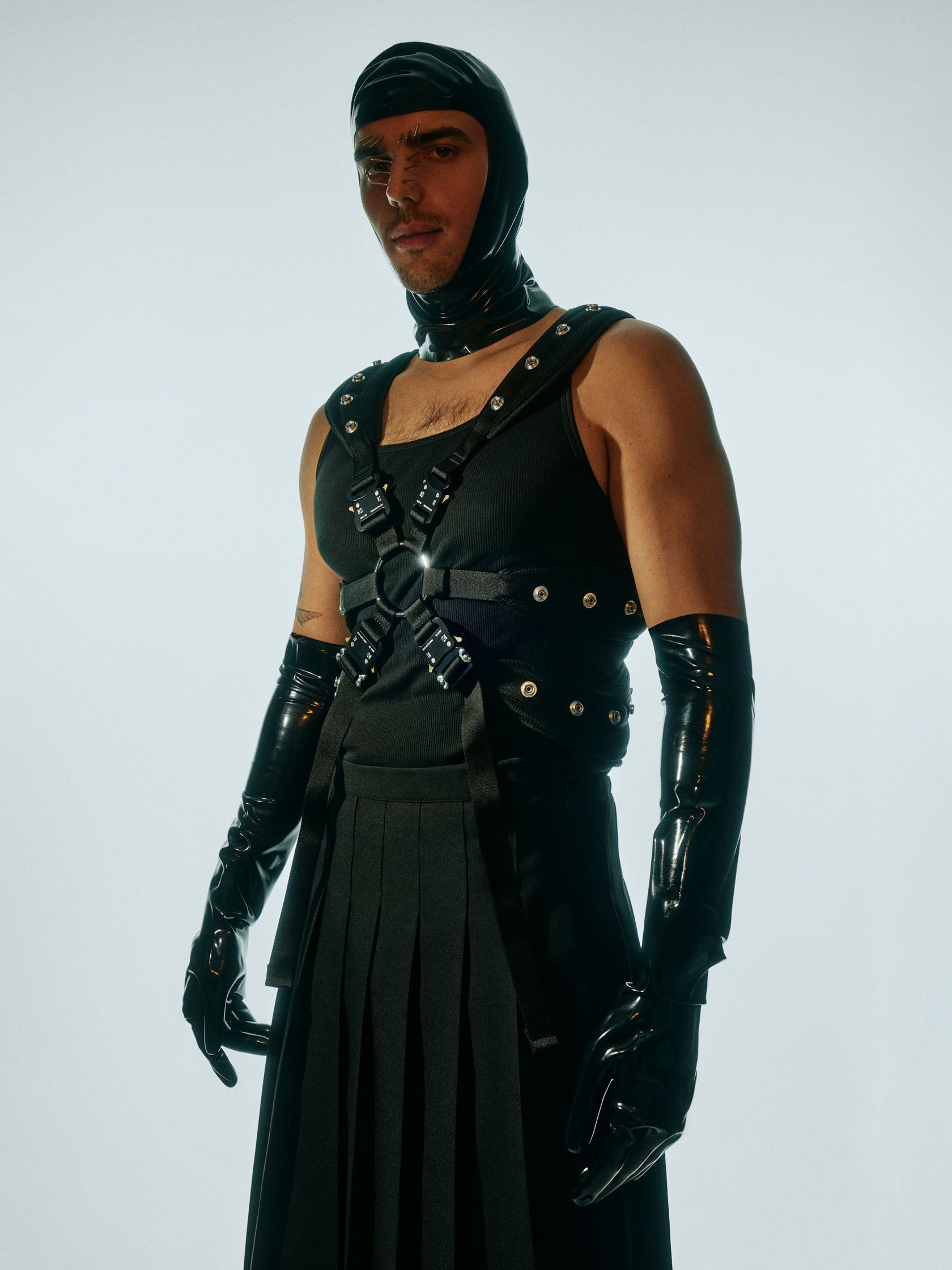 a man in a latex outfit posing in front of a white background