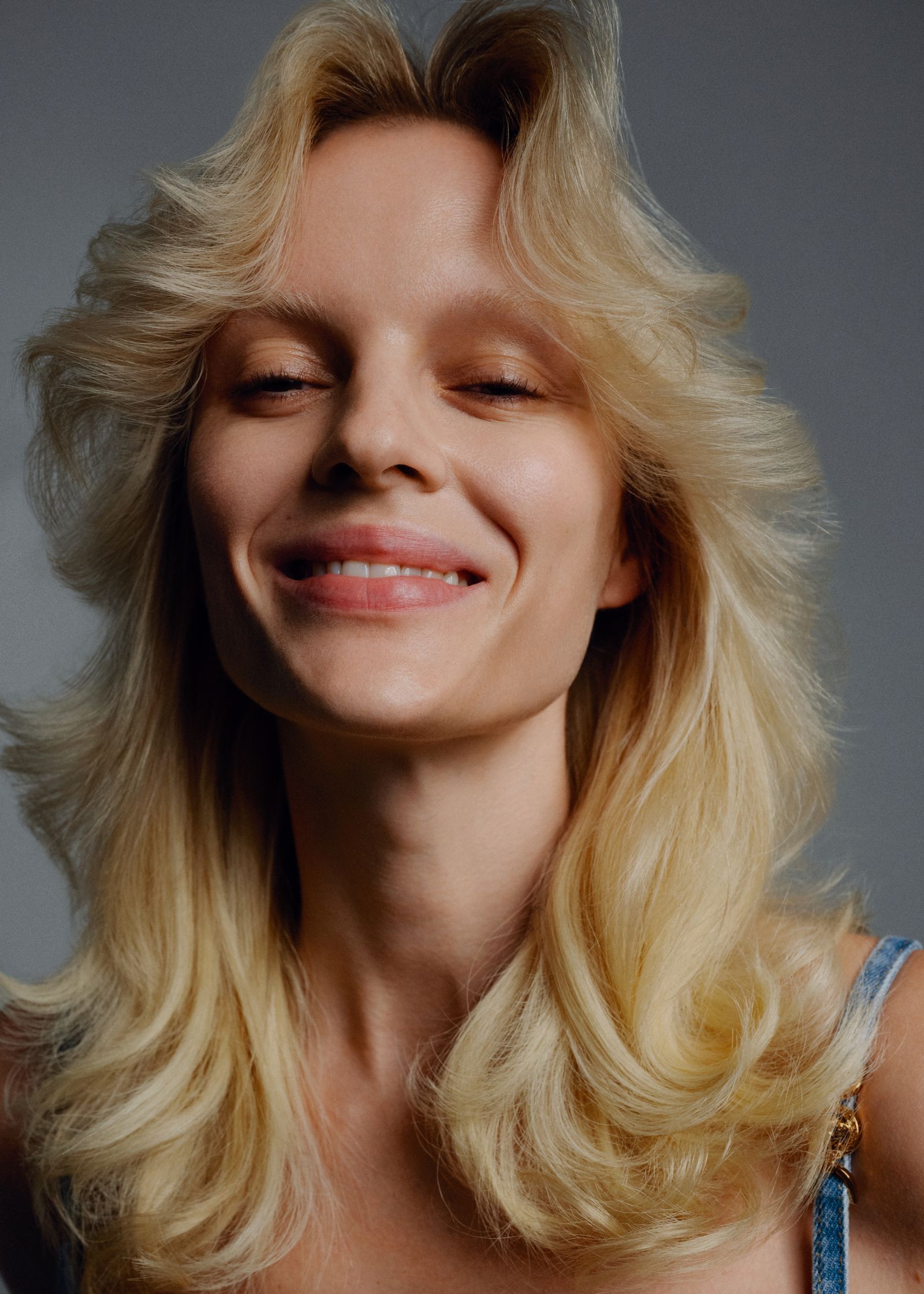 a woman with long blonde hair smiling at the camera
