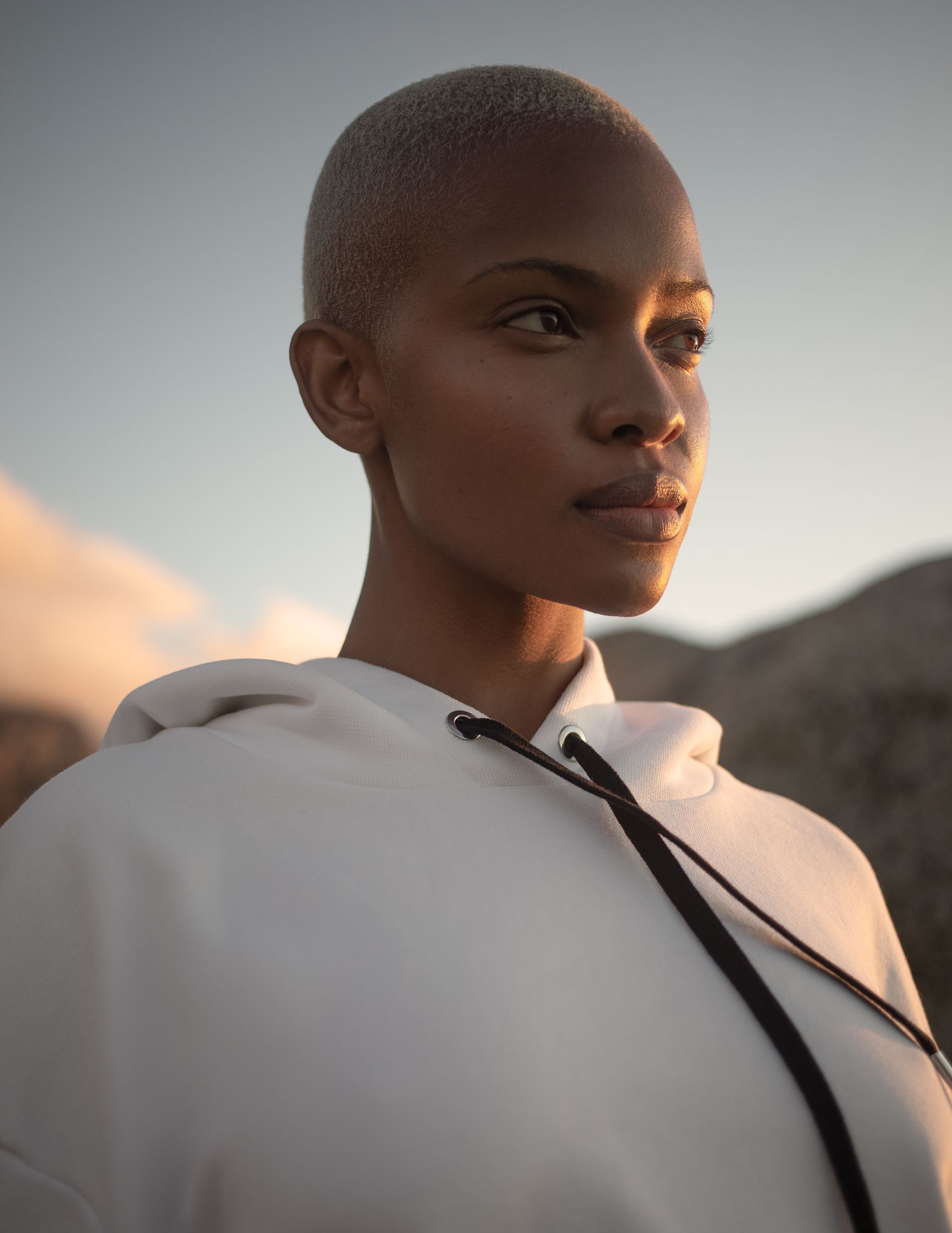 a woman in a white hoodie with a shaved head