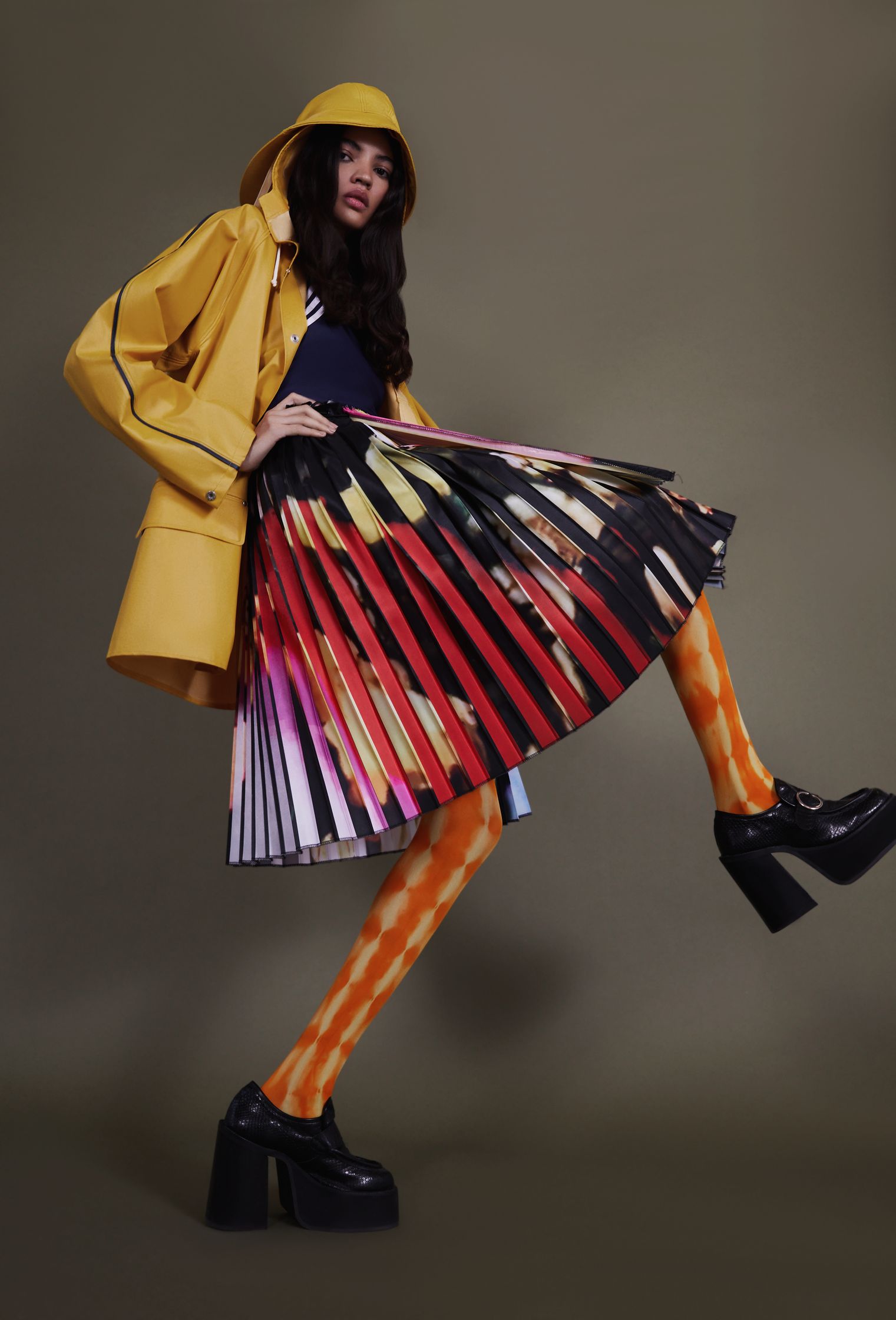 a woman in a yellow raincoat and pleated skirt