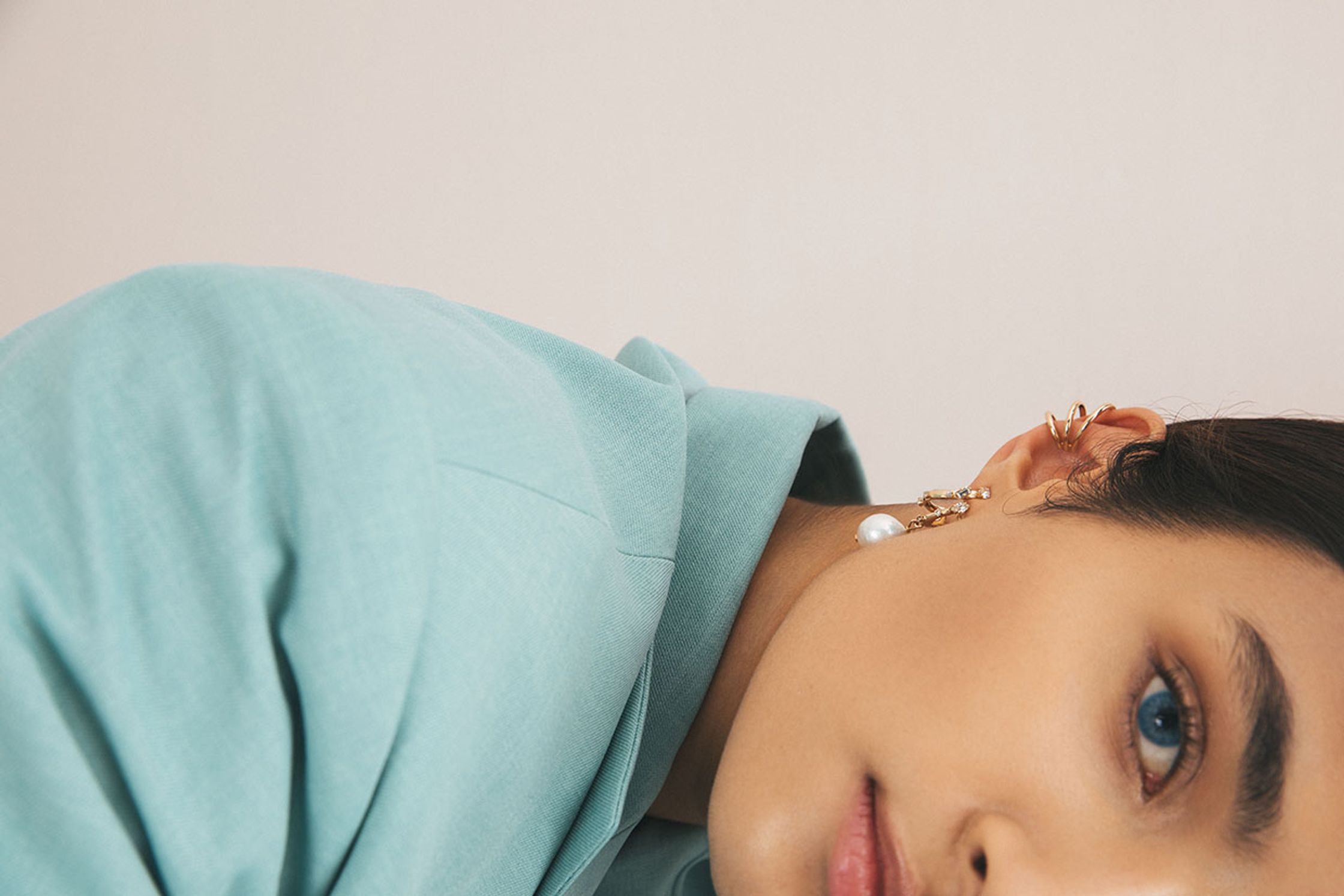 a woman wearing a blue shirt and ear cuffs