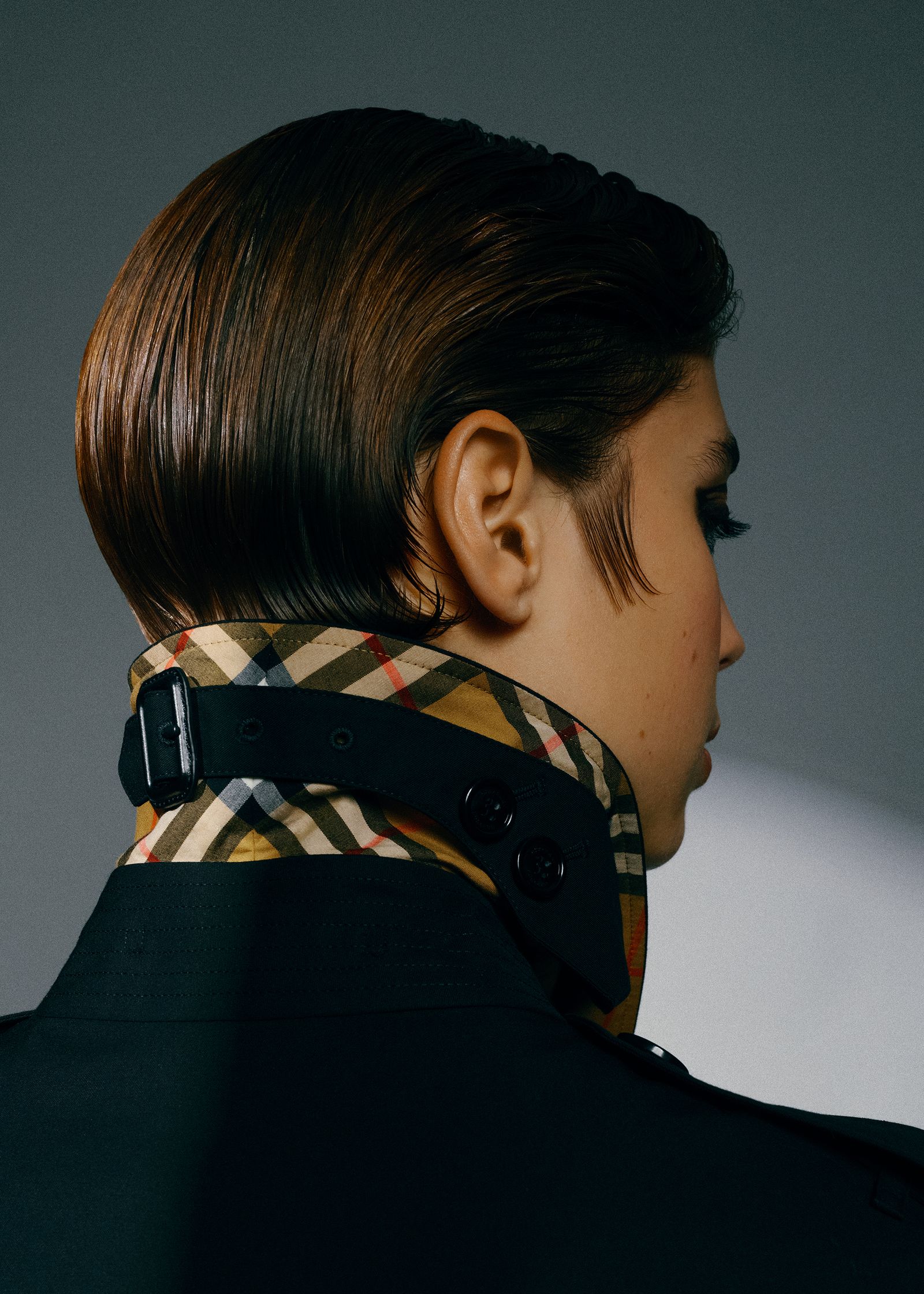 a woman wearing a black coat with a check collar