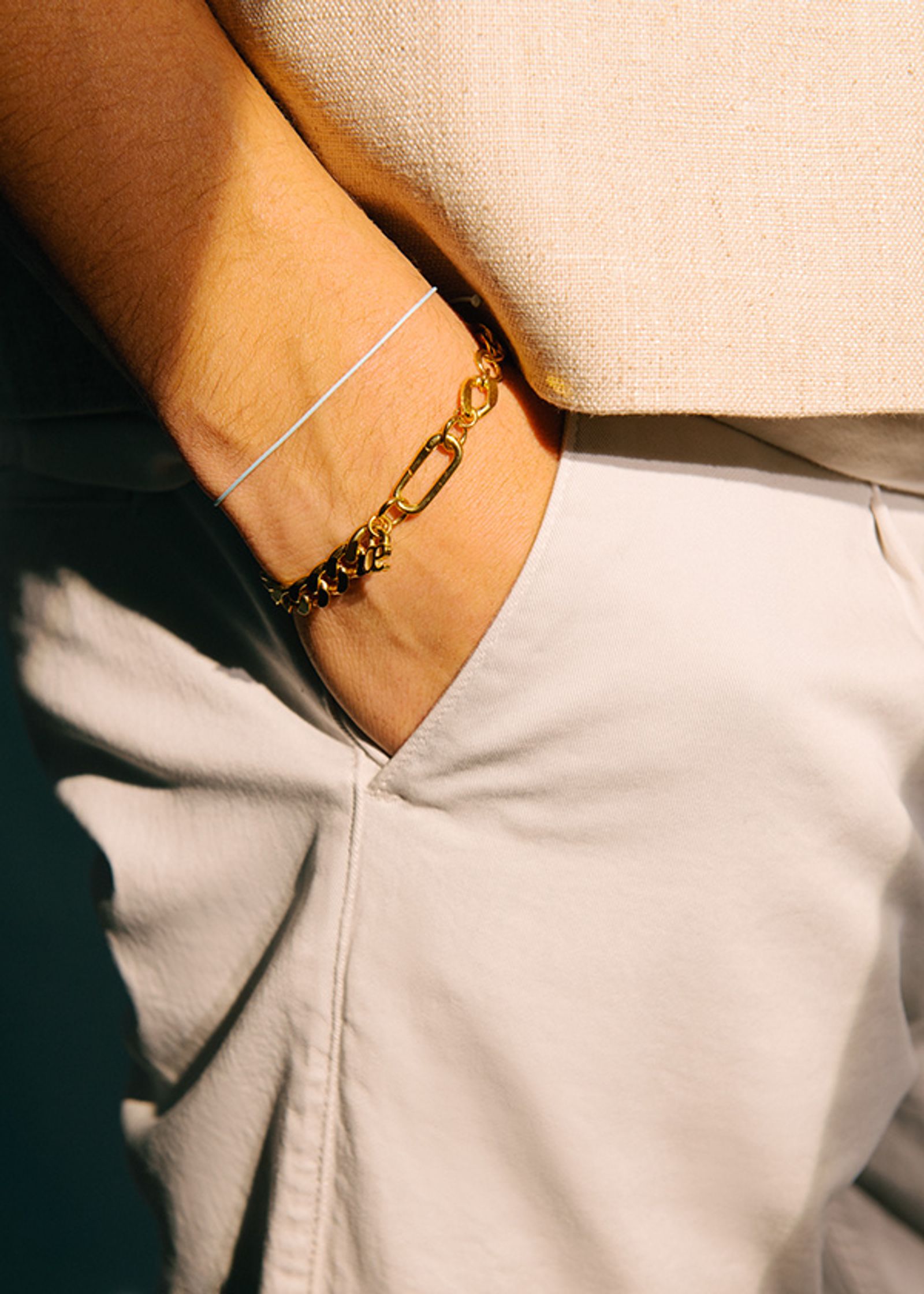 a person wearing white pants and a gold bracelet