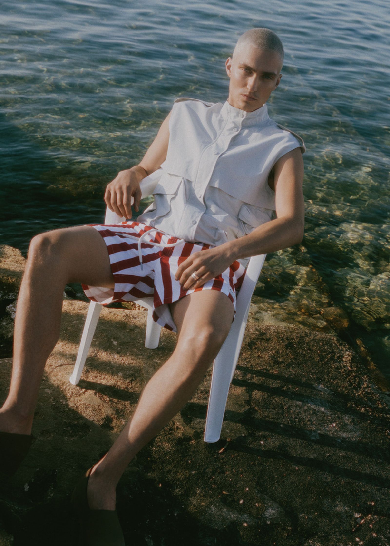 a man sitting on a chair next to the water