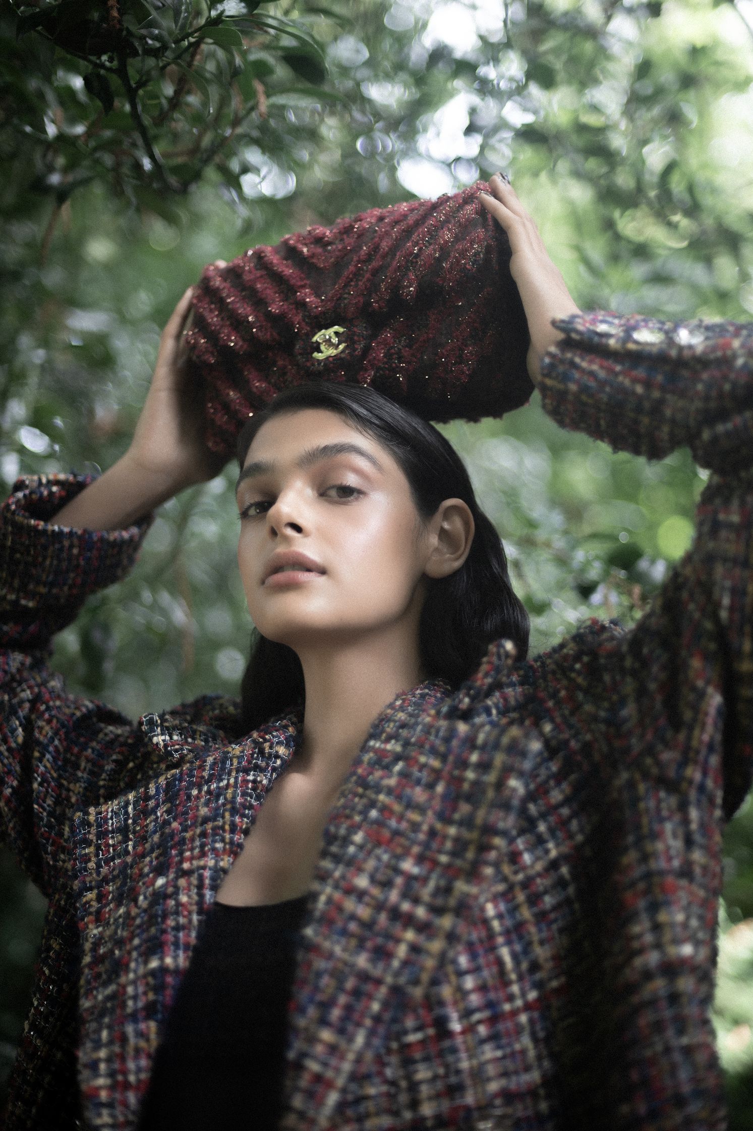 a woman holding a tweed hat in the woods