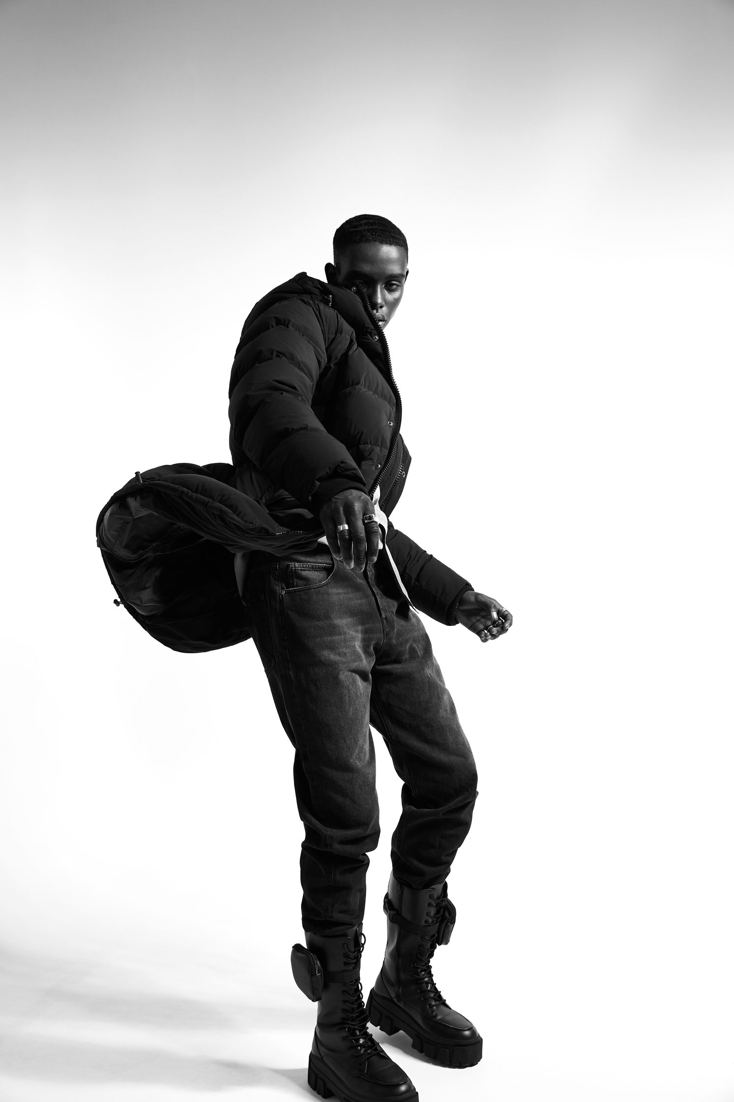 a black and white photo of a man in a jacket and boots